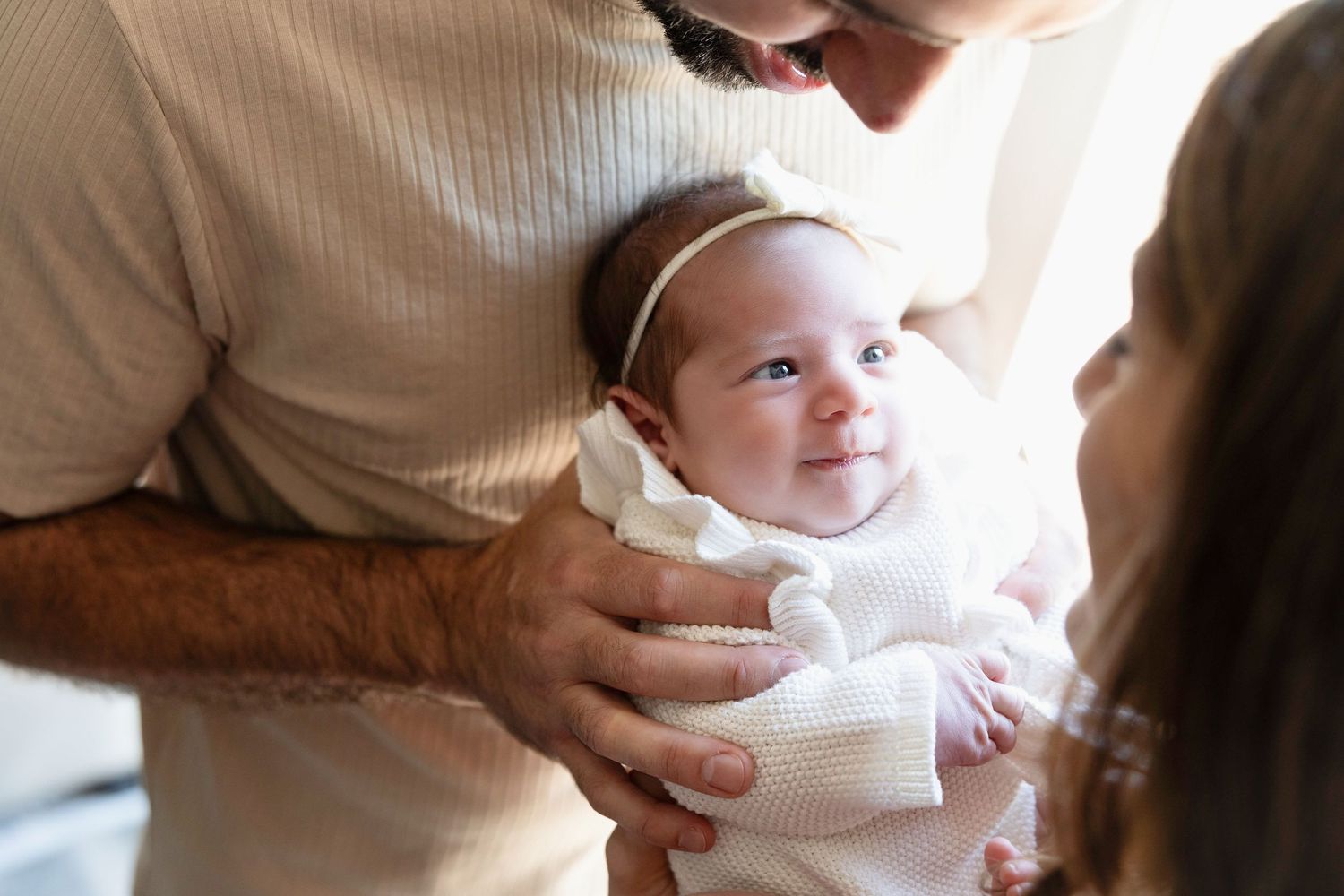 Parents share tender moment with newborn baby during in-home photography session.