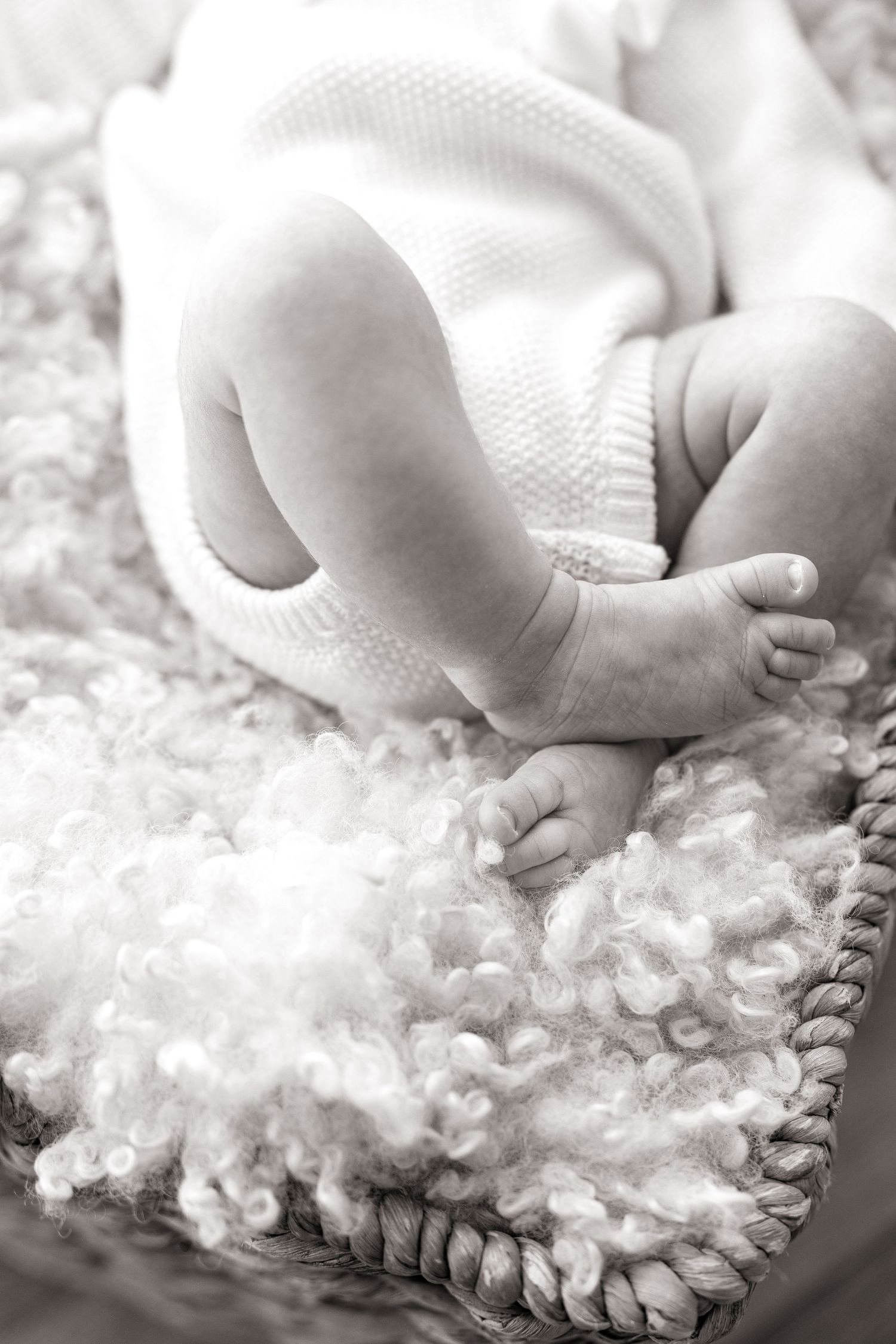 Close-up of tiny newborn feet resting on textured white blanket.
