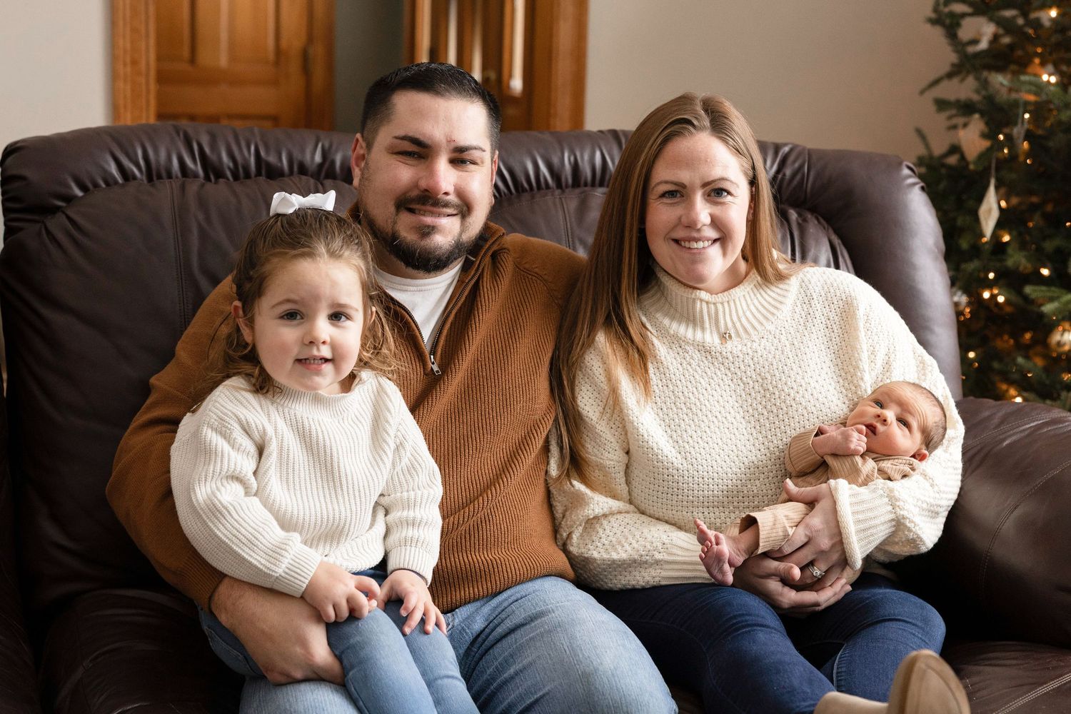 Cozy indoor family session with Christmas tree in background.