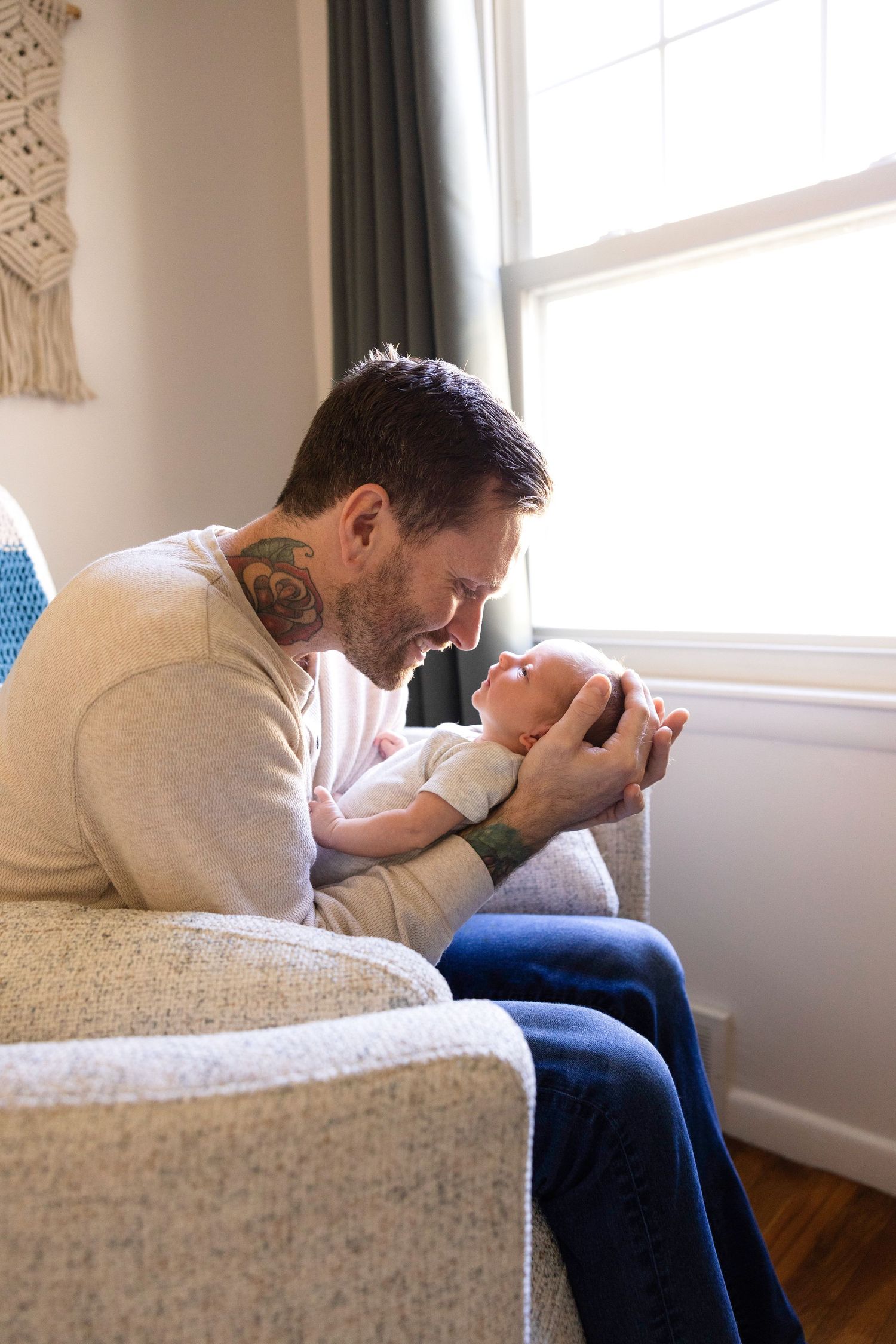 Tender moment between parent and baby in sunlit room.