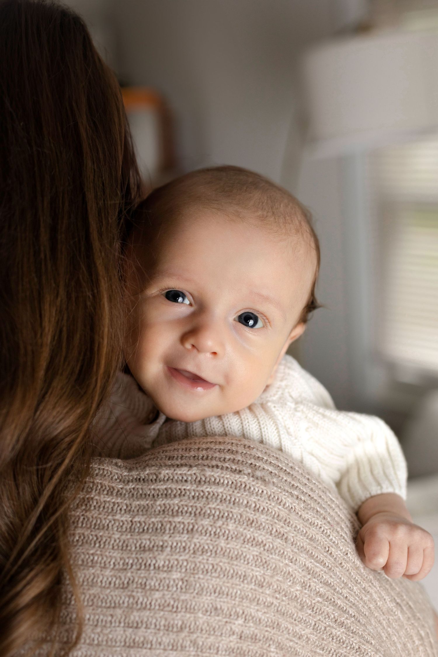 Close up of baby peeking over shoulder during indoor portrait session.