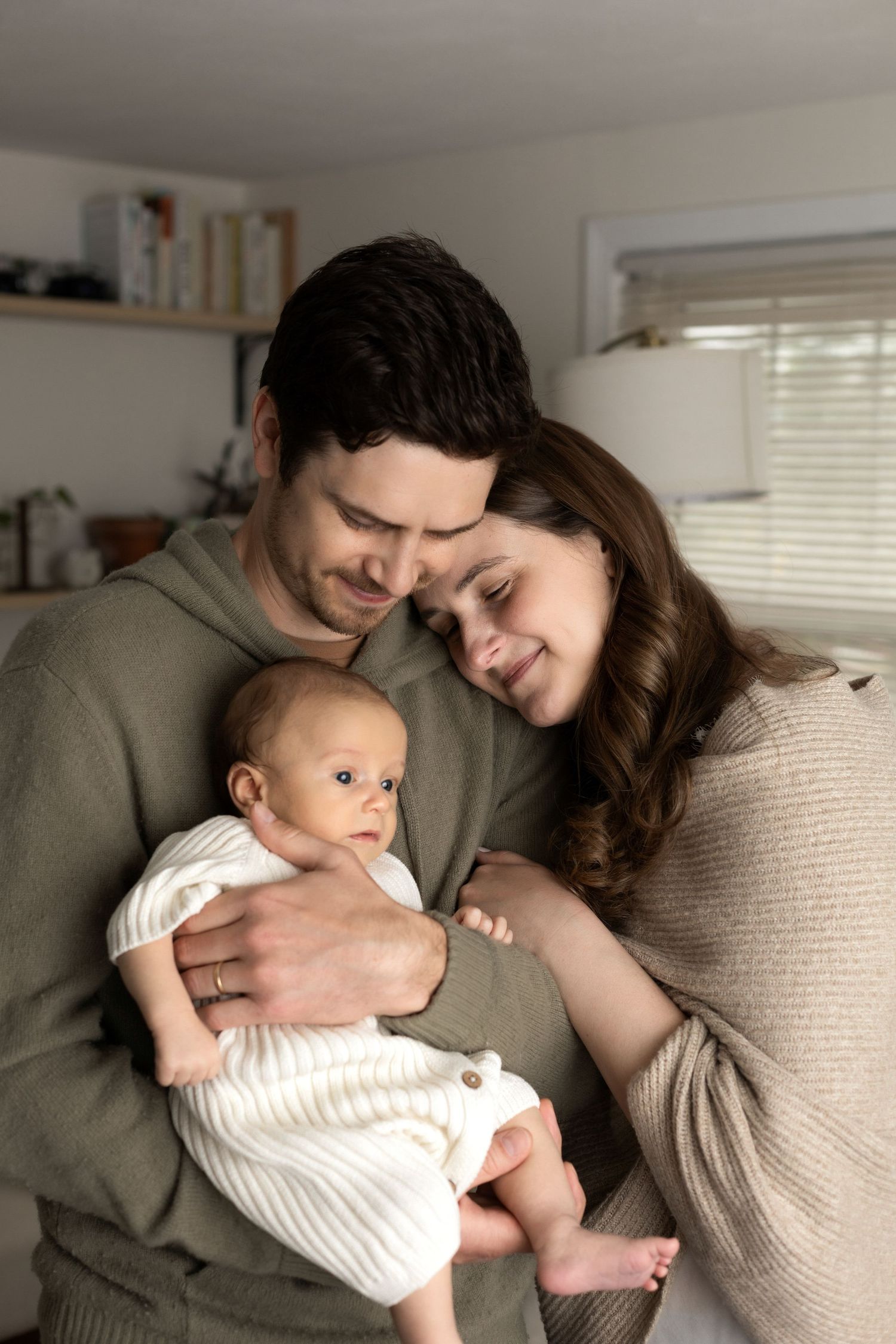 Family cuddles together on couch during intimate indoor photo session.