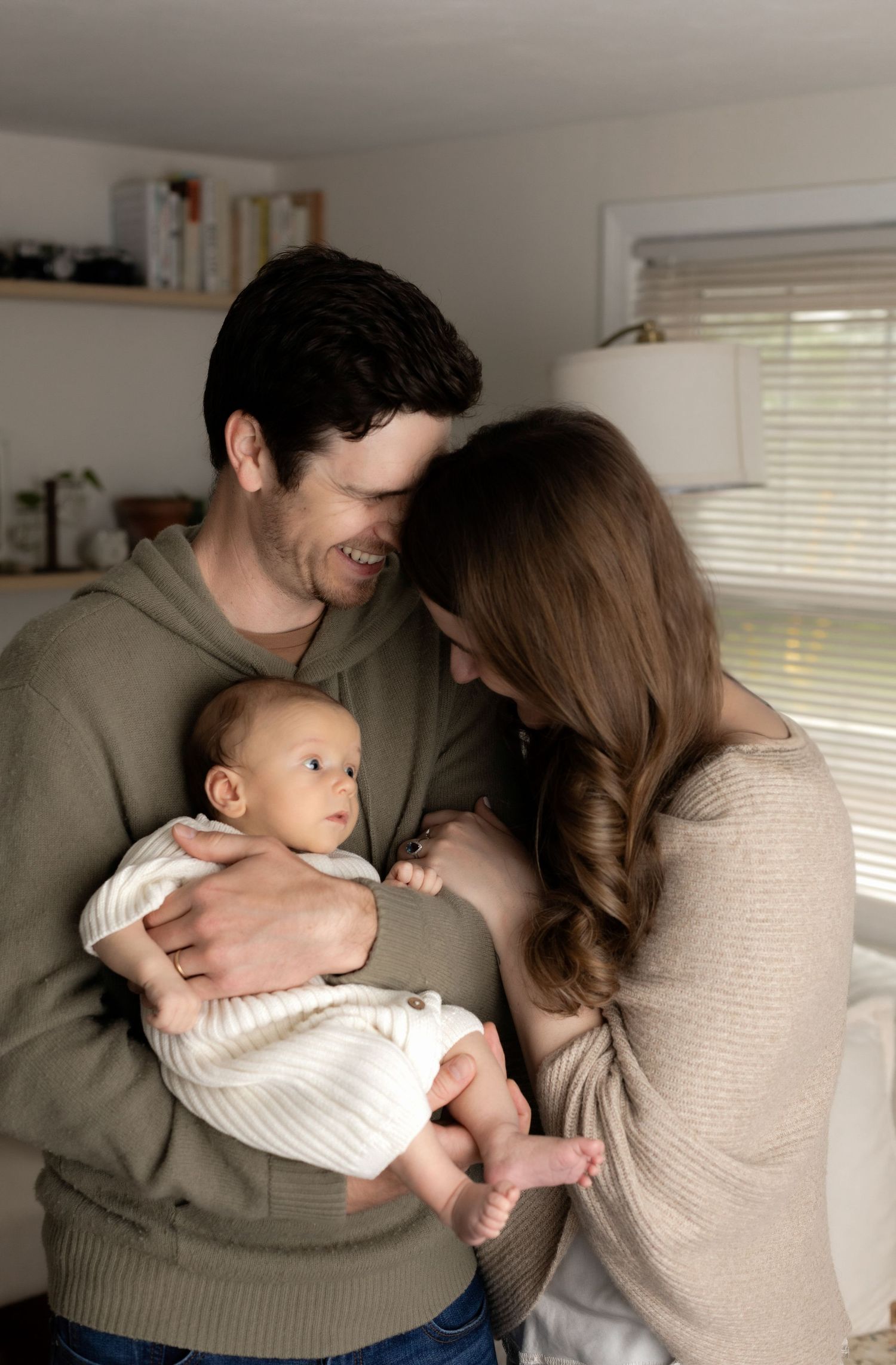 Parents share tender moment with baby during home photography session.