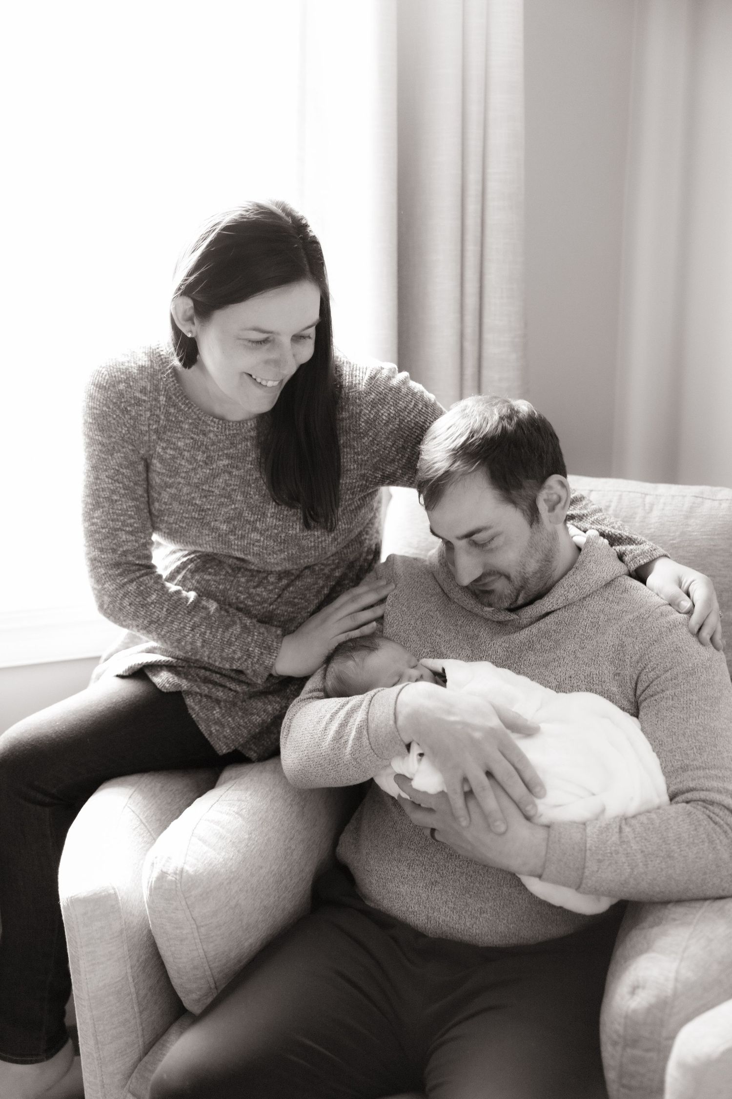 Intimate black and white photos of family bonding on couch near window.