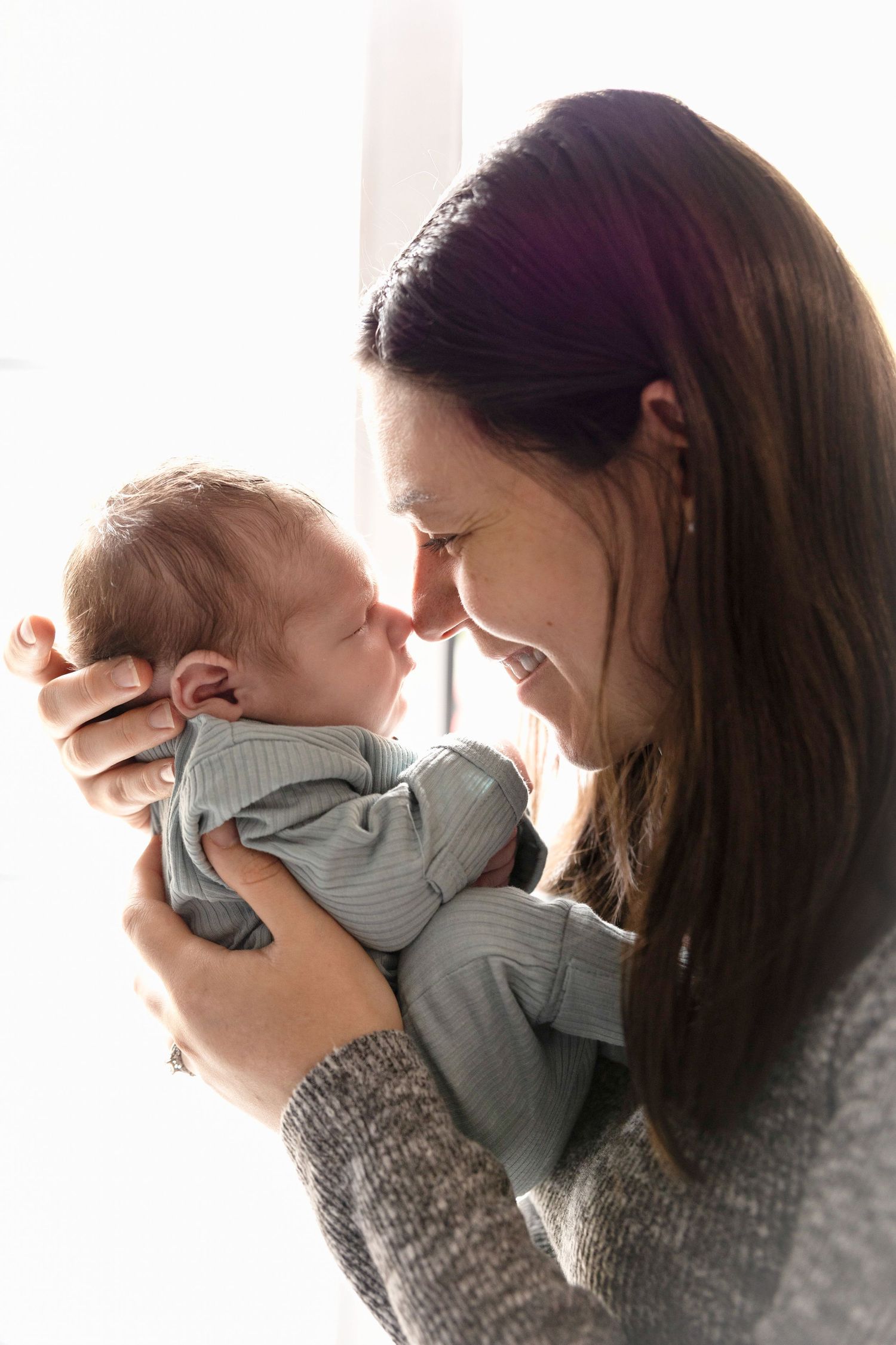 Tender moments captured between parent and baby in natural window light.