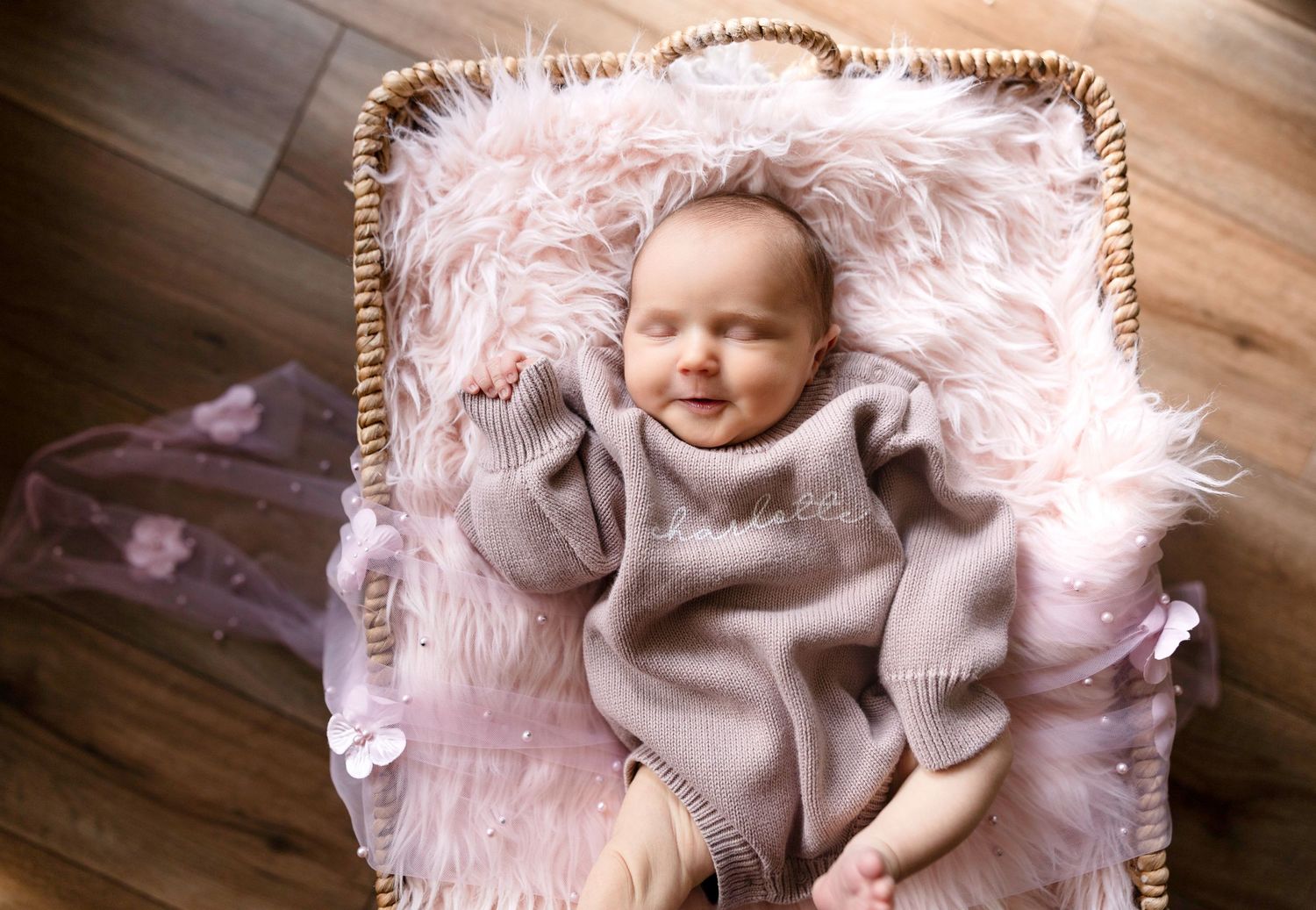 A newborn lies on a soft pink blanket during a professional photography session.