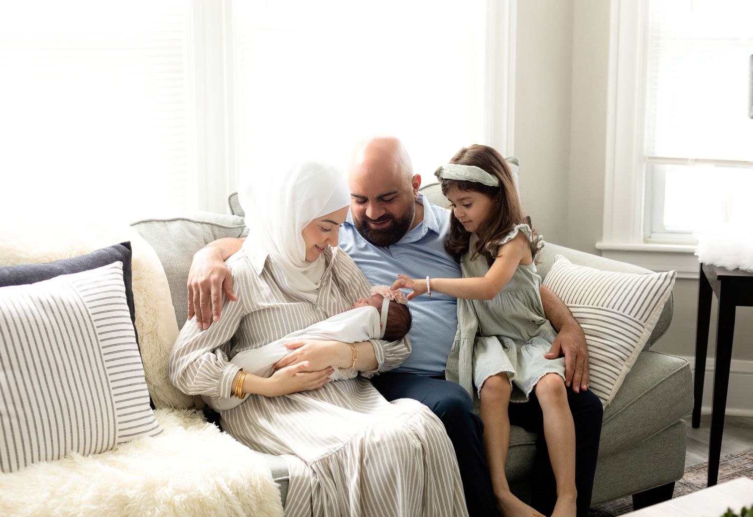 Family enjoying quality time together on a cozy striped sofa in a bright living room.