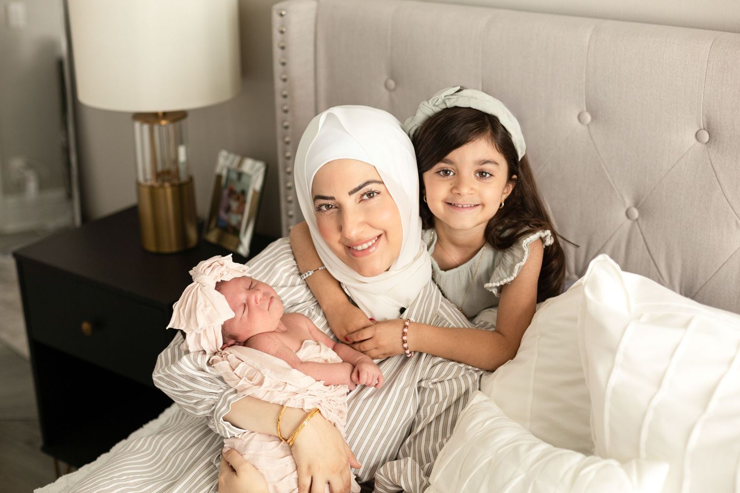 Mother and child sharing a tender moment while resting on a gray tufted headboard bed.
