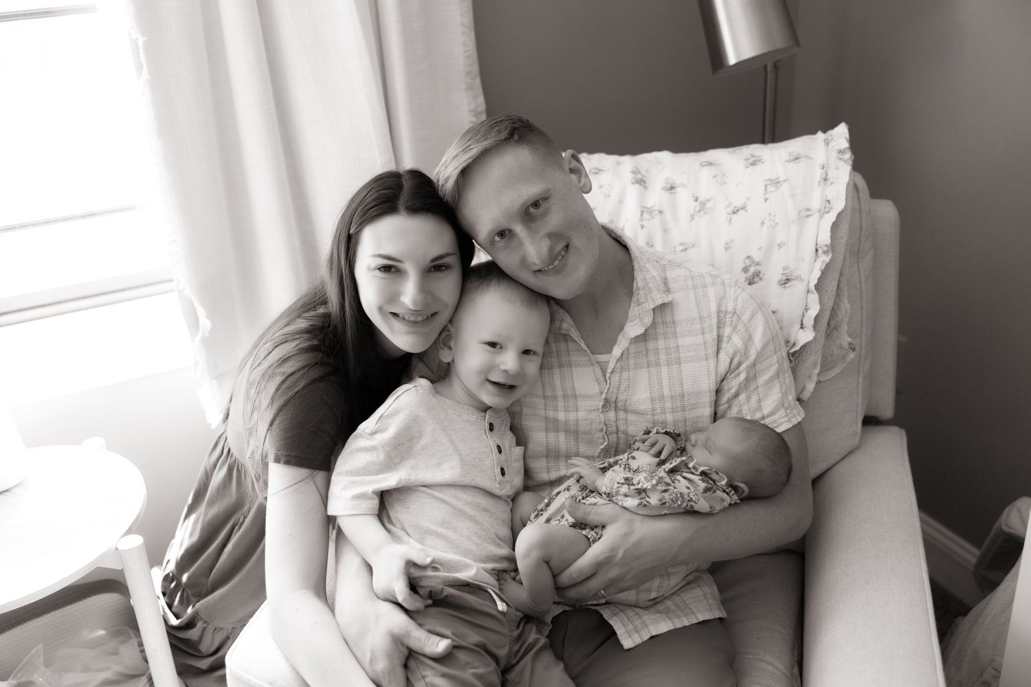 A family shares intimate black and white moments with their newborn baby.
