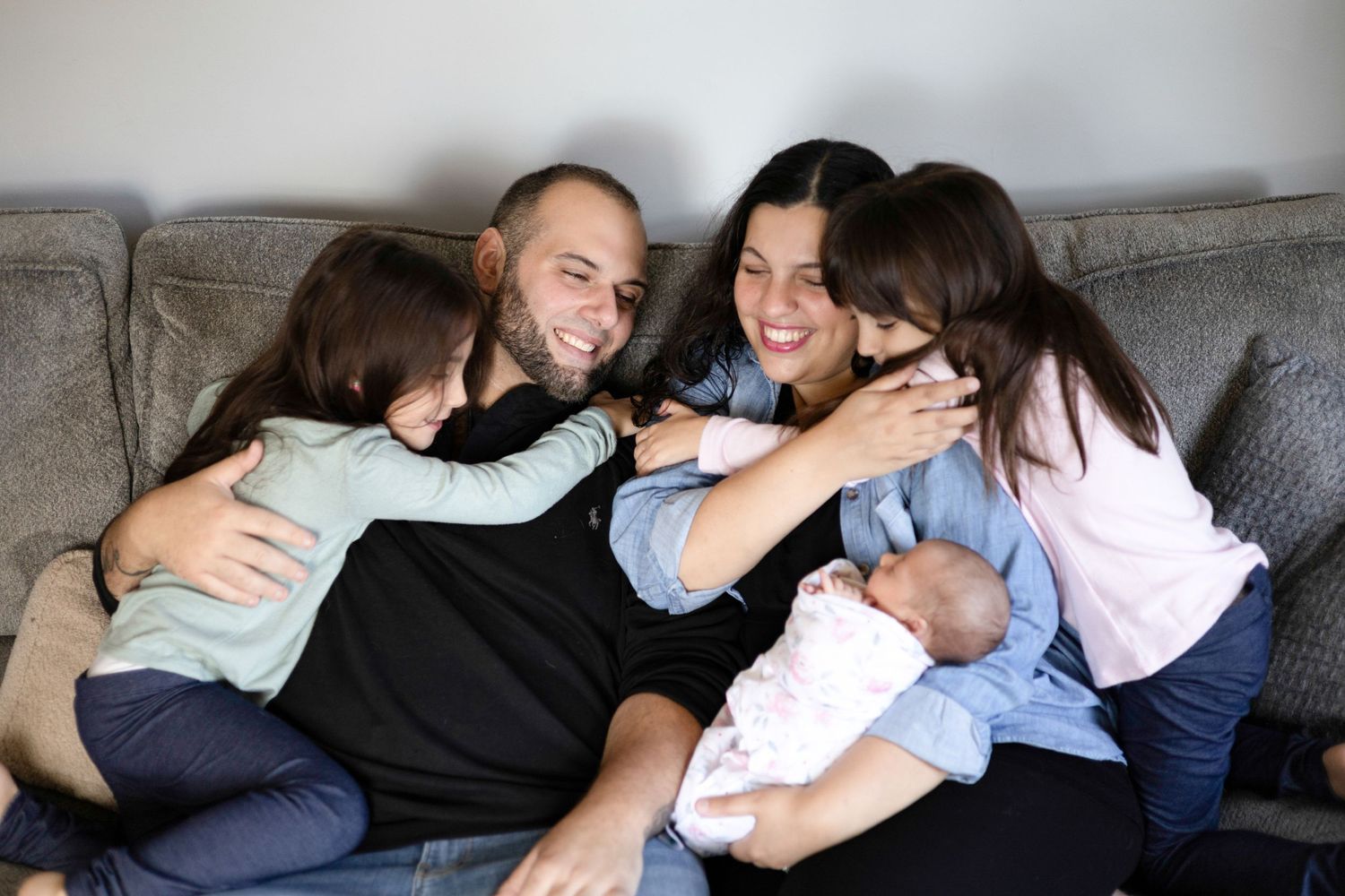 Candid family photography session showing relaxed poses on grey sofa.