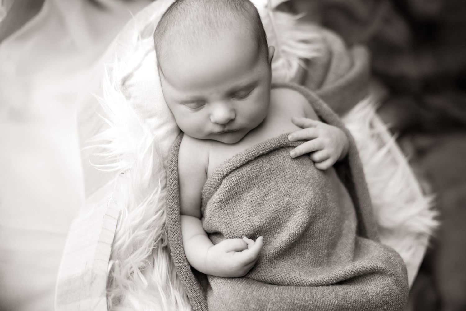 Black and white photo series of a sleeping newborn baby wrapped in soft blankets.
