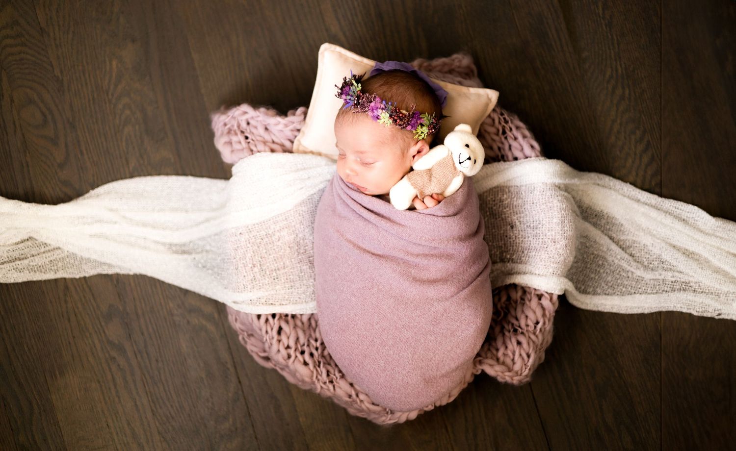 Artistic newborn photography sequence showing a baby wrapped in pink lace against a dark background.