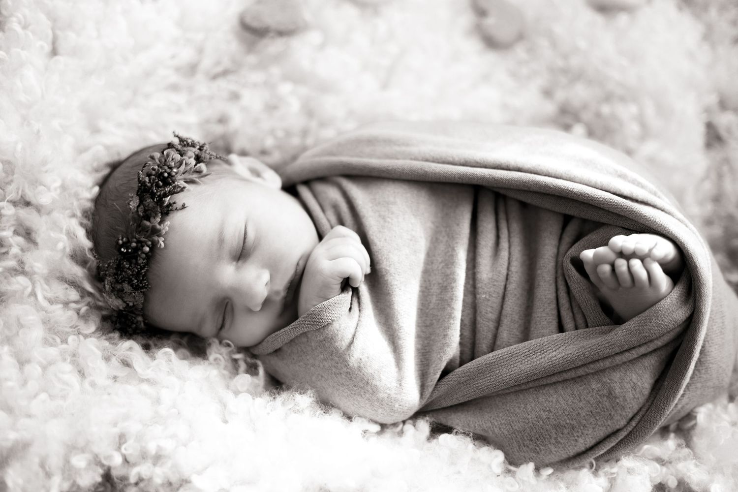 Artistic black and white newborn portraits with soft white fabric wrapping.