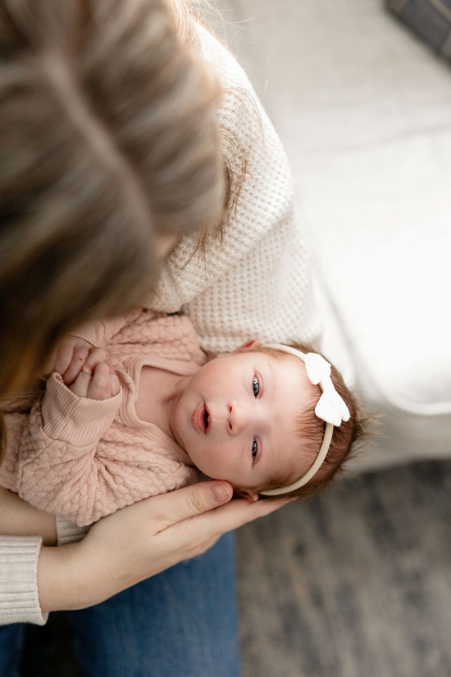 Sweet baby in pink outfit lying on soft blanket during lifestyle photography session.