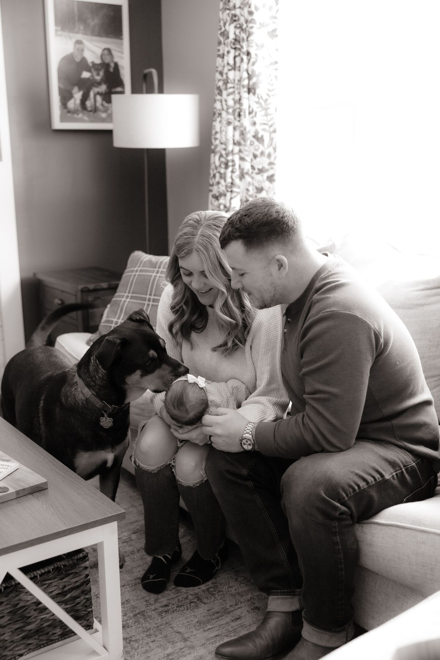 Intimate lifestyle family photo session with couple cuddling on couch in living room.