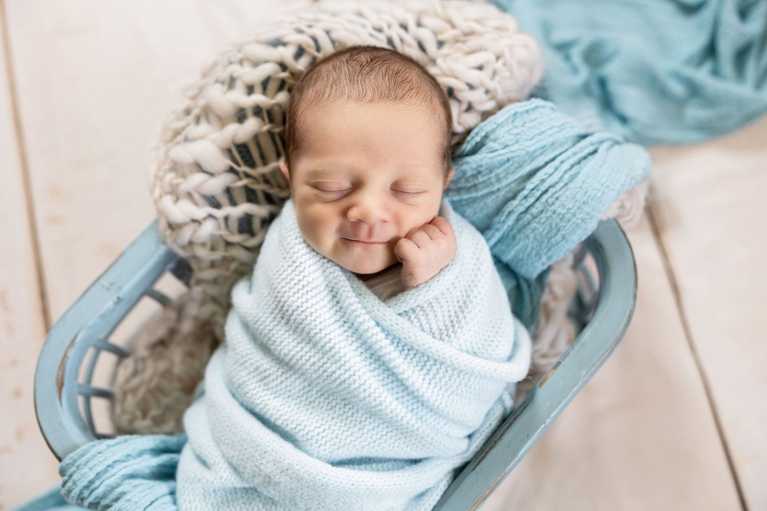 Series of newborn photos with baby wrapped in soft blue knit blanket.