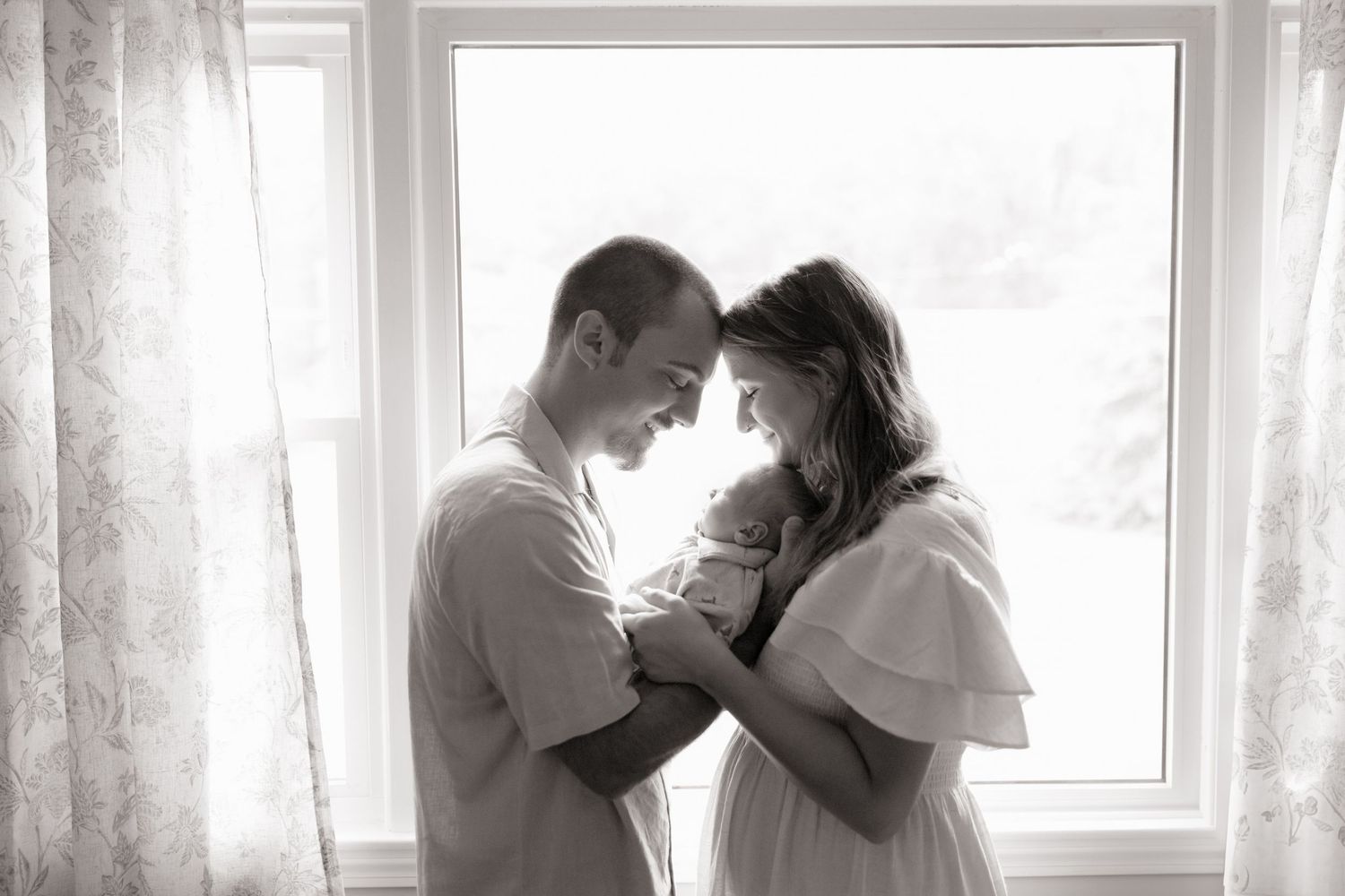 A series of intimate monochrome portraits showing tender moments between a couple against a window.