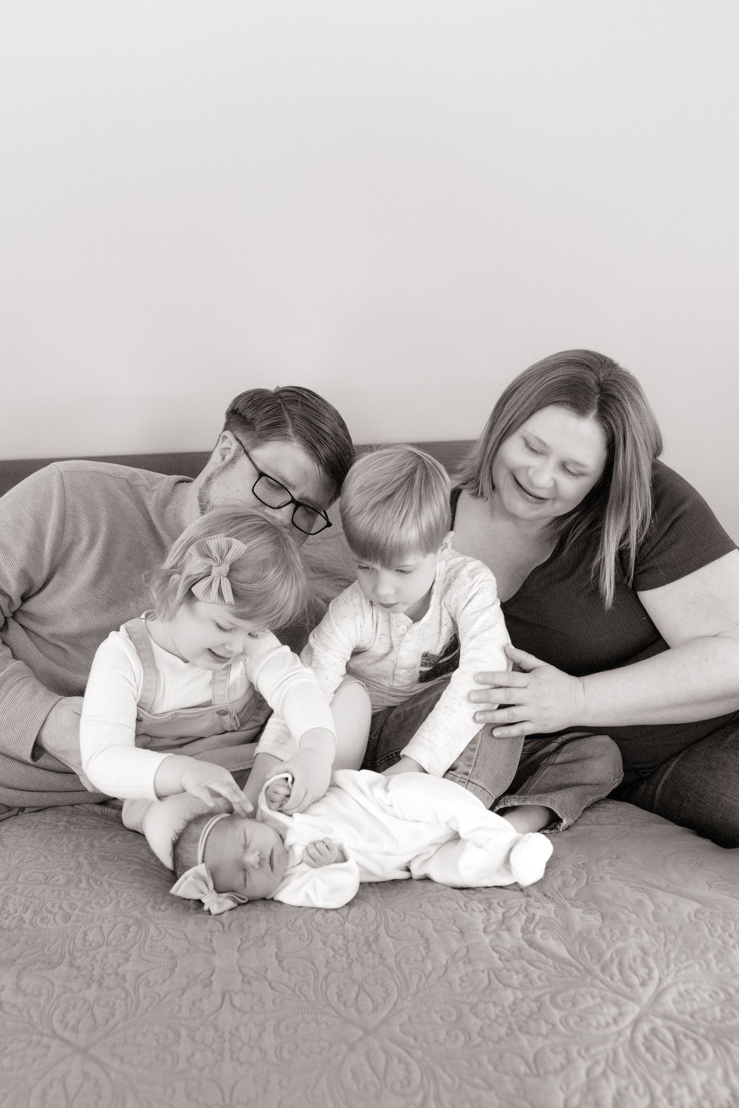 Family lounges together on grey couch in black and white portrait series.