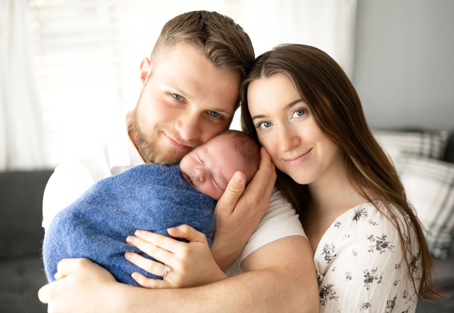 Tender family moment showing parents cuddling with their newborn baby on white background.