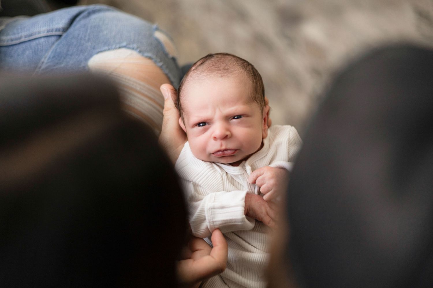 Close up of newborn baby resting on soft textured surface in natural lighting.