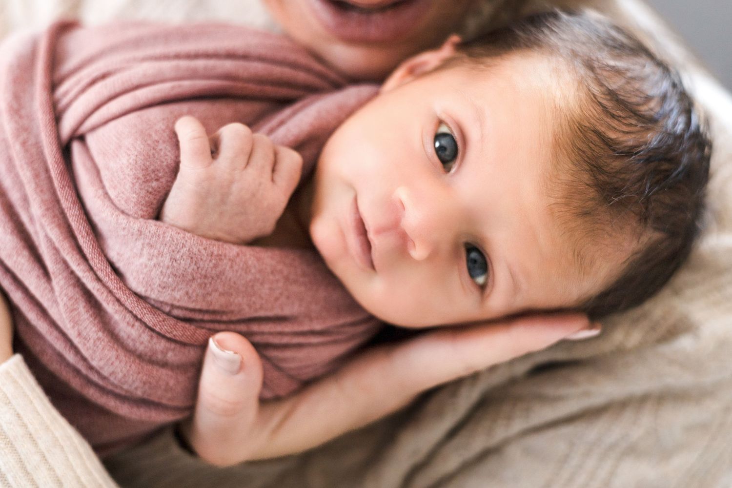 Child in pink sweater poses for candid lifestyle portraits on light background.