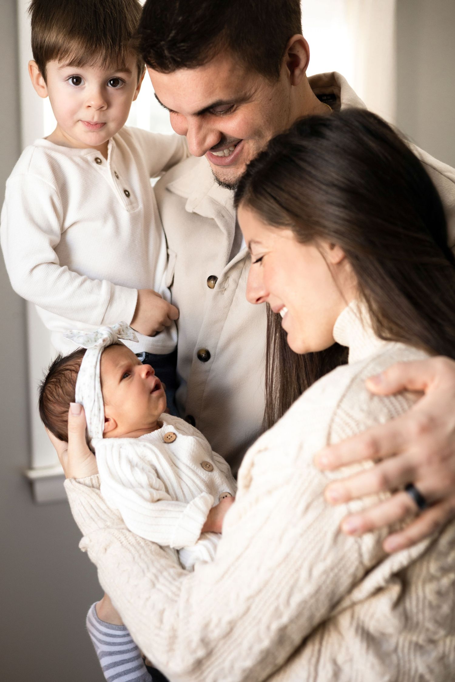 Family cuddles together in matching white outfits during intimate photo session.
