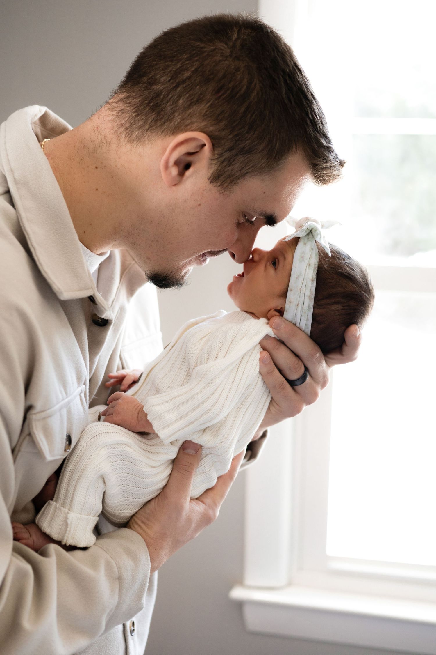 Intimate black and white portrait series of parent holding and kissing newborn.