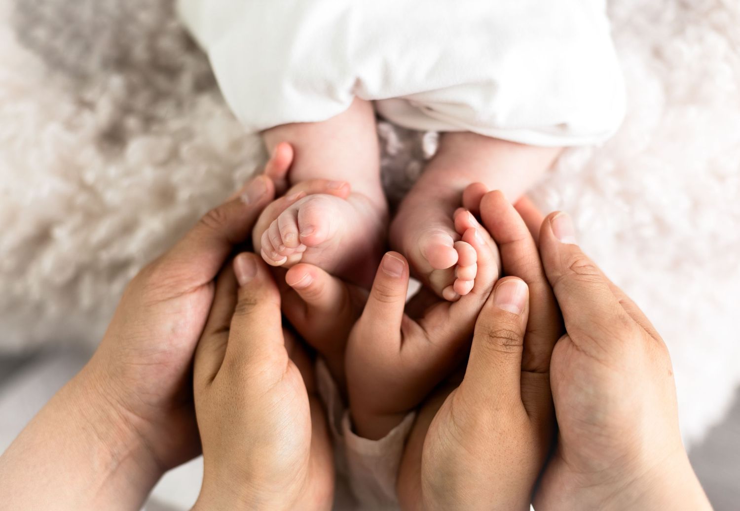 Close-up of tiny baby feet being gently held by adult hands.