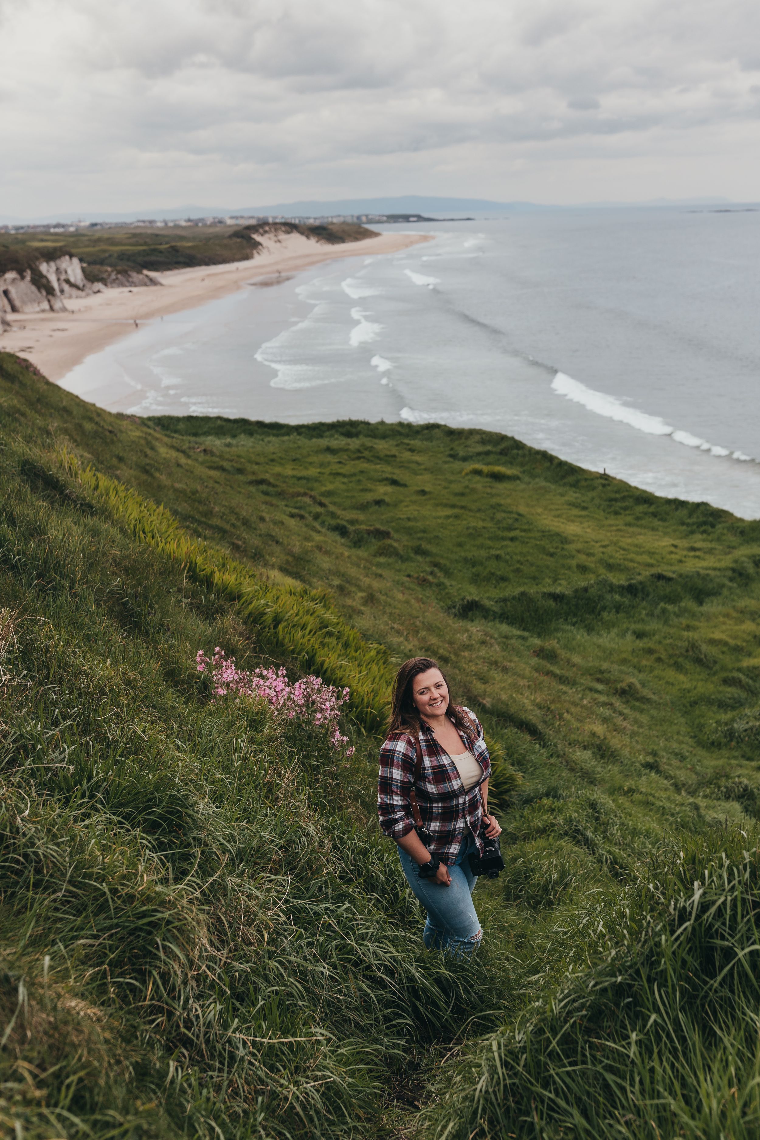 Scenic coastal cliffside overlooking a sandy beach and rolling waves.