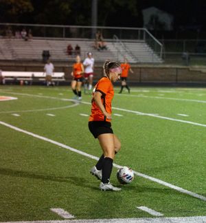 Soccer player in orange uniform prepares to take a corner kick on field during night game.