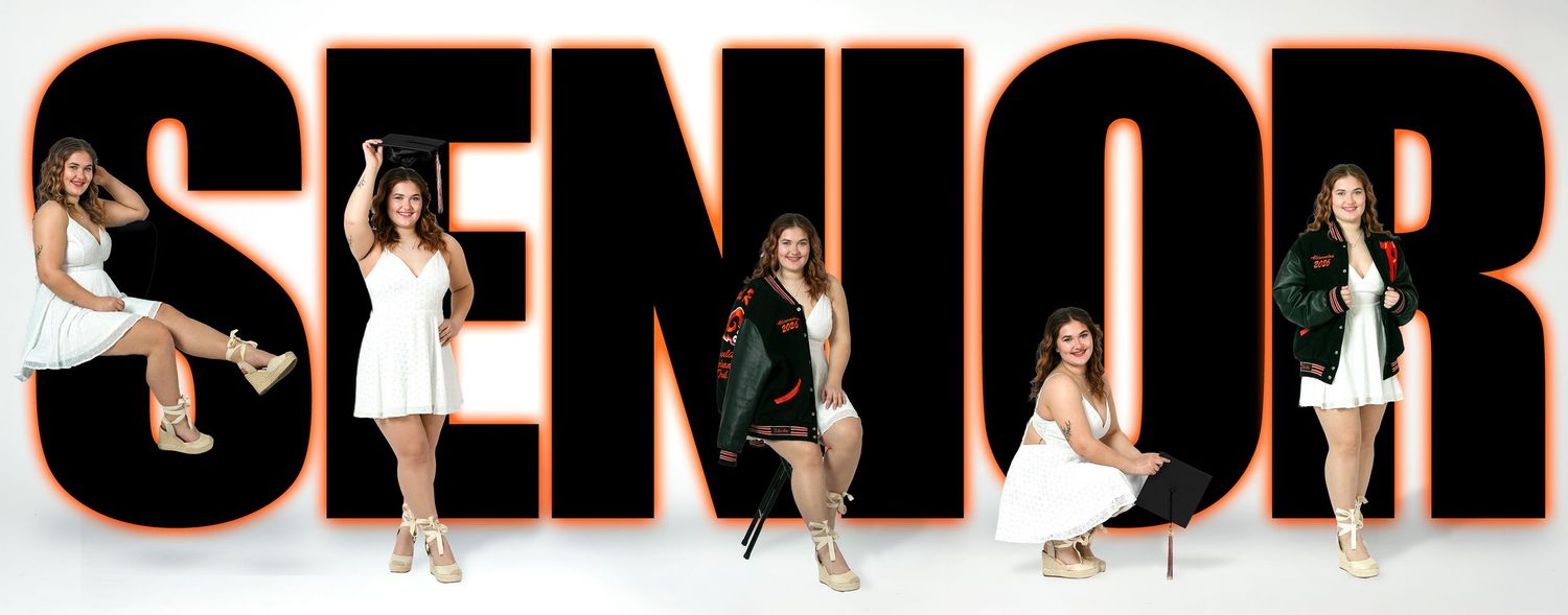 Five young women pose in white dresses among large SENIOR letters for a graduation photo session.
