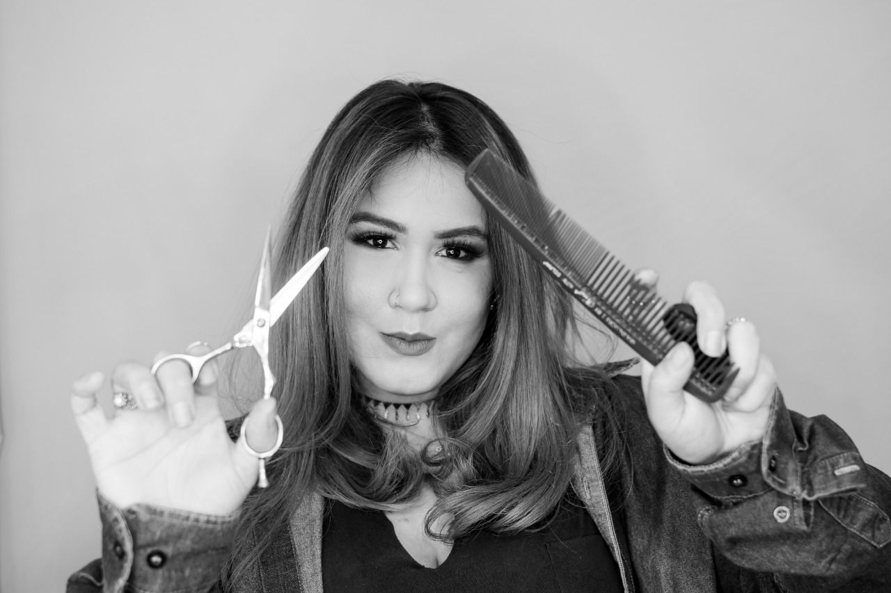 Black and white photo of someone playfully cutting their own hair with scissors.