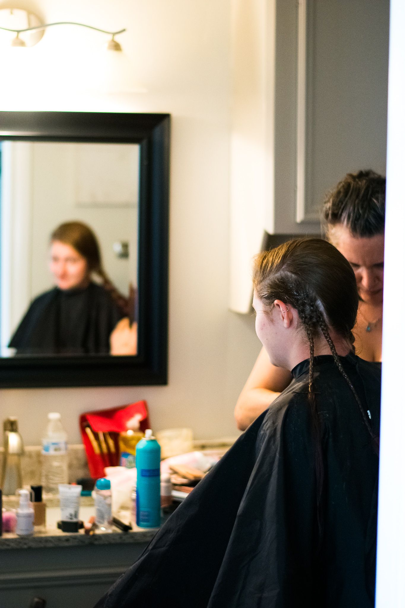 Hair styling session in progress at a salon with styling products visible on counter.