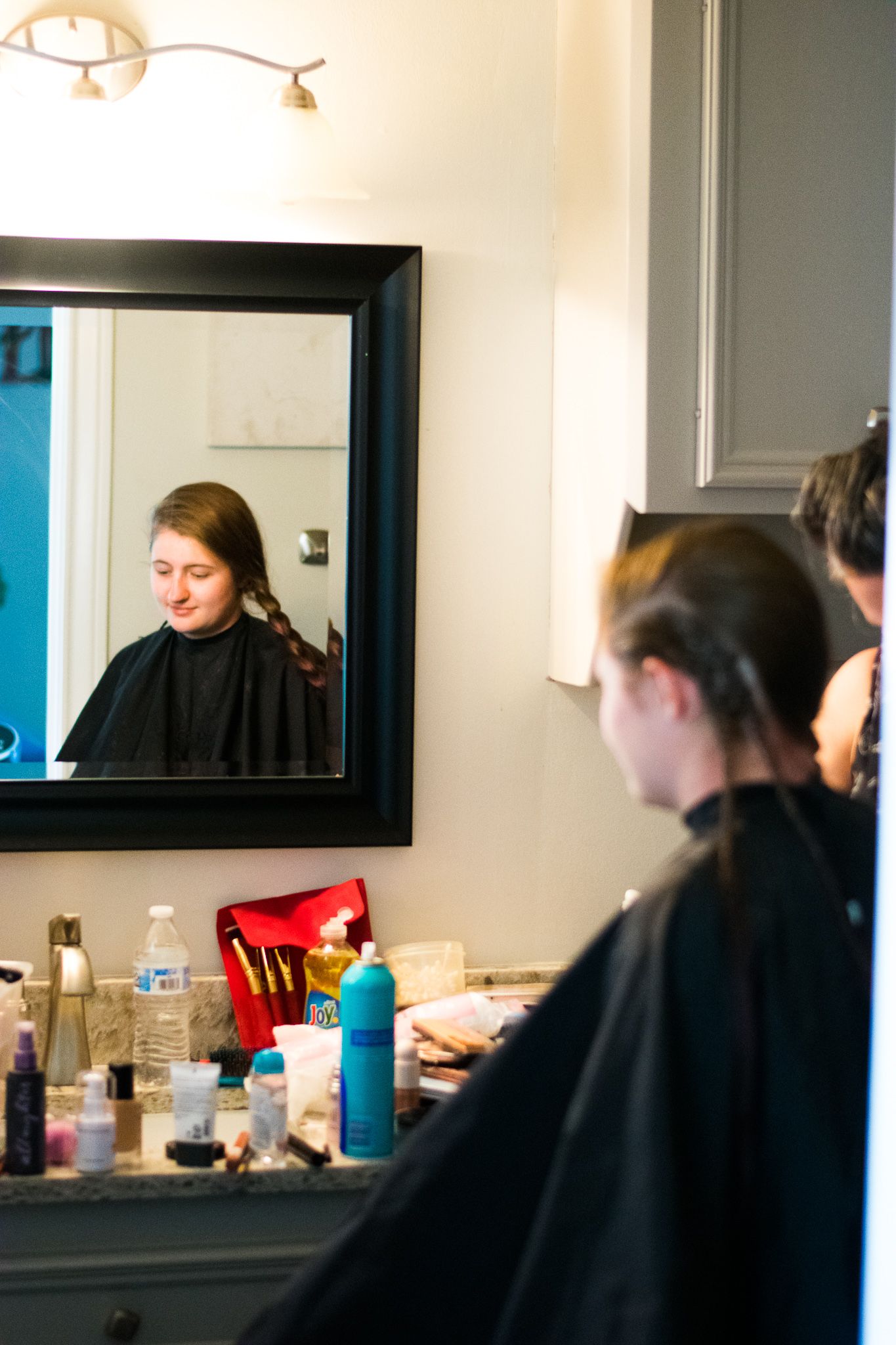 Mirror reflection shows hair styling preparation with products arranged on vanity counter.