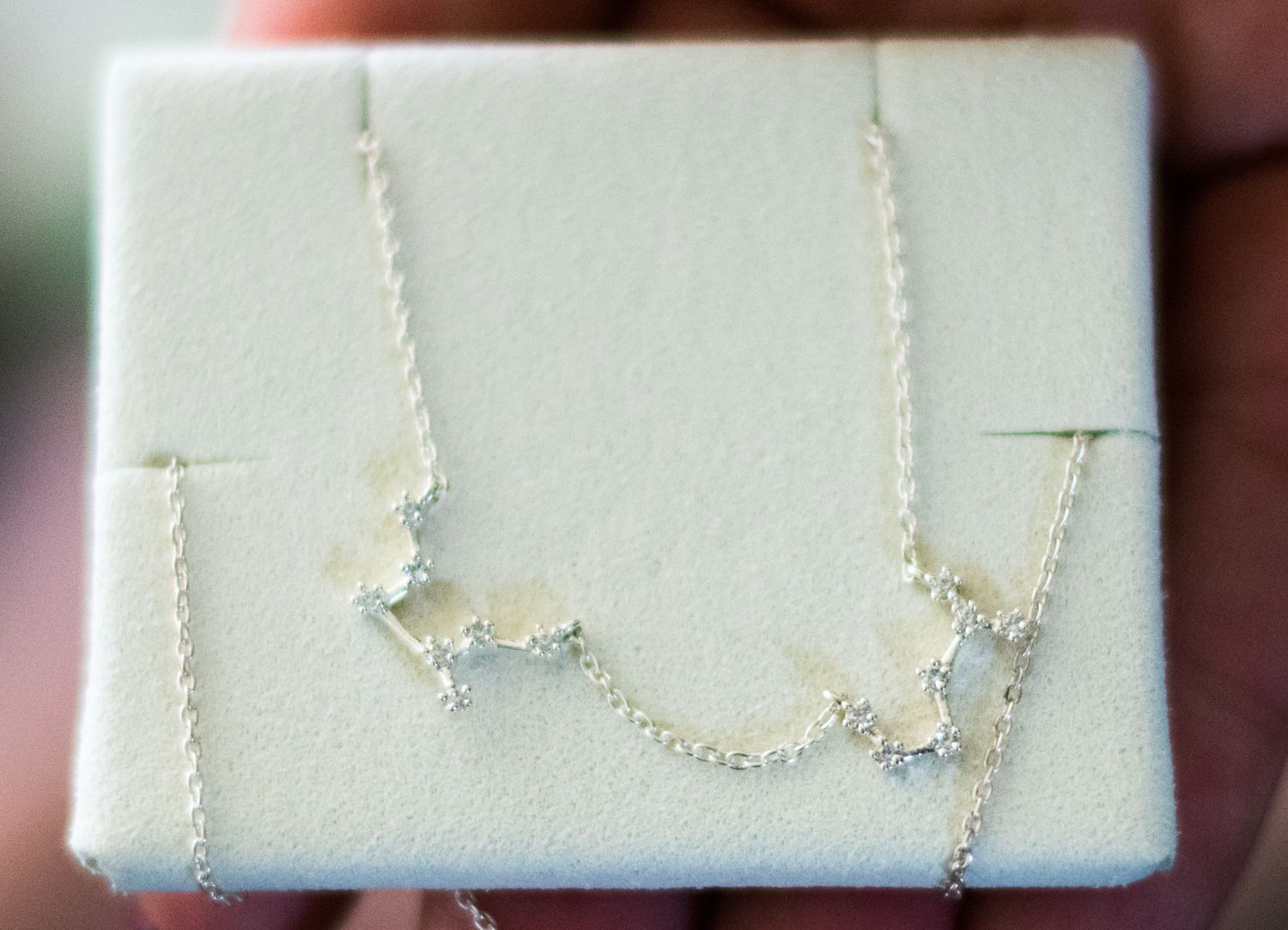 Delicate silver constellation necklace displayed on white jewelry box.