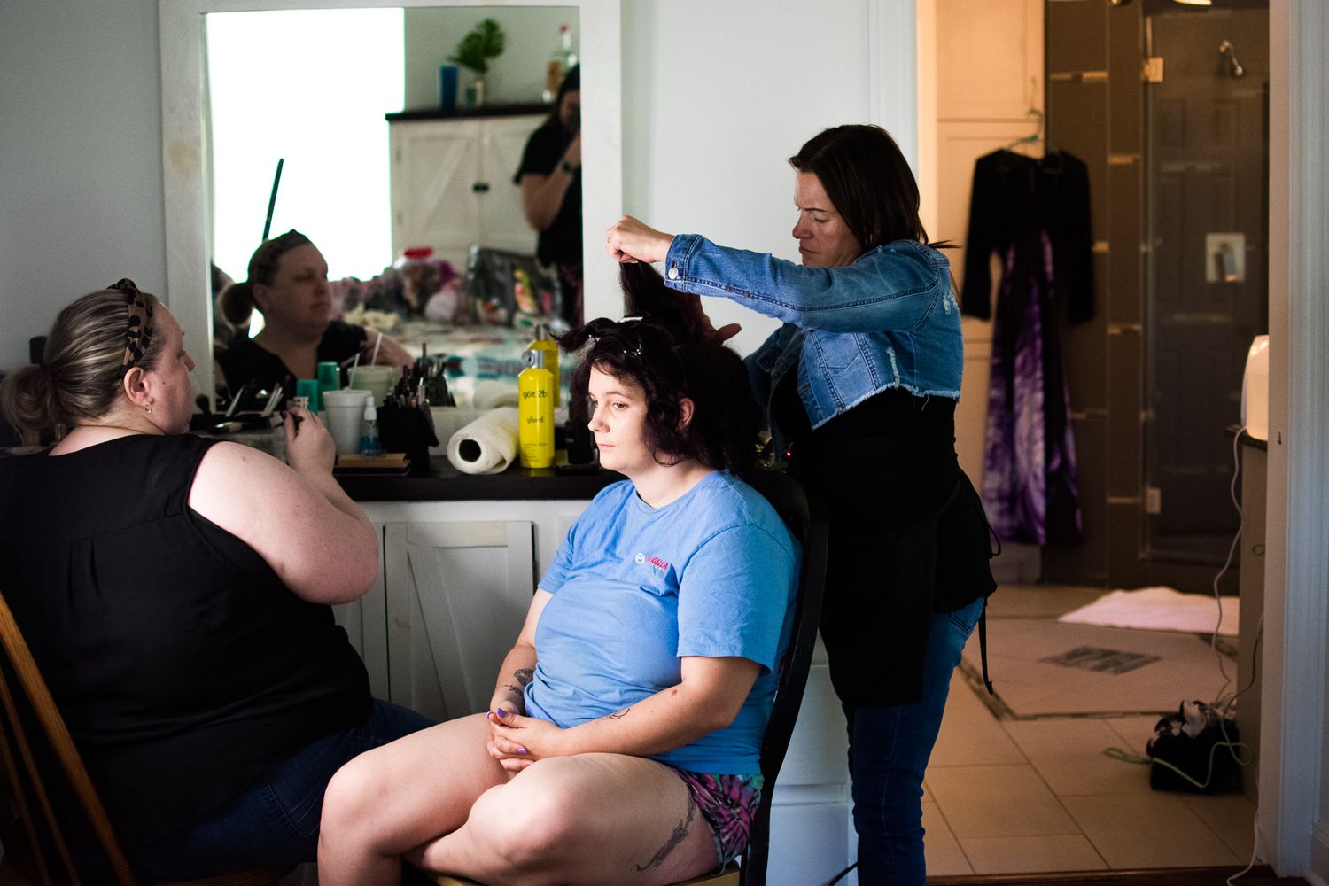 Hair styling session in progress with multiple people in a casual home setting.