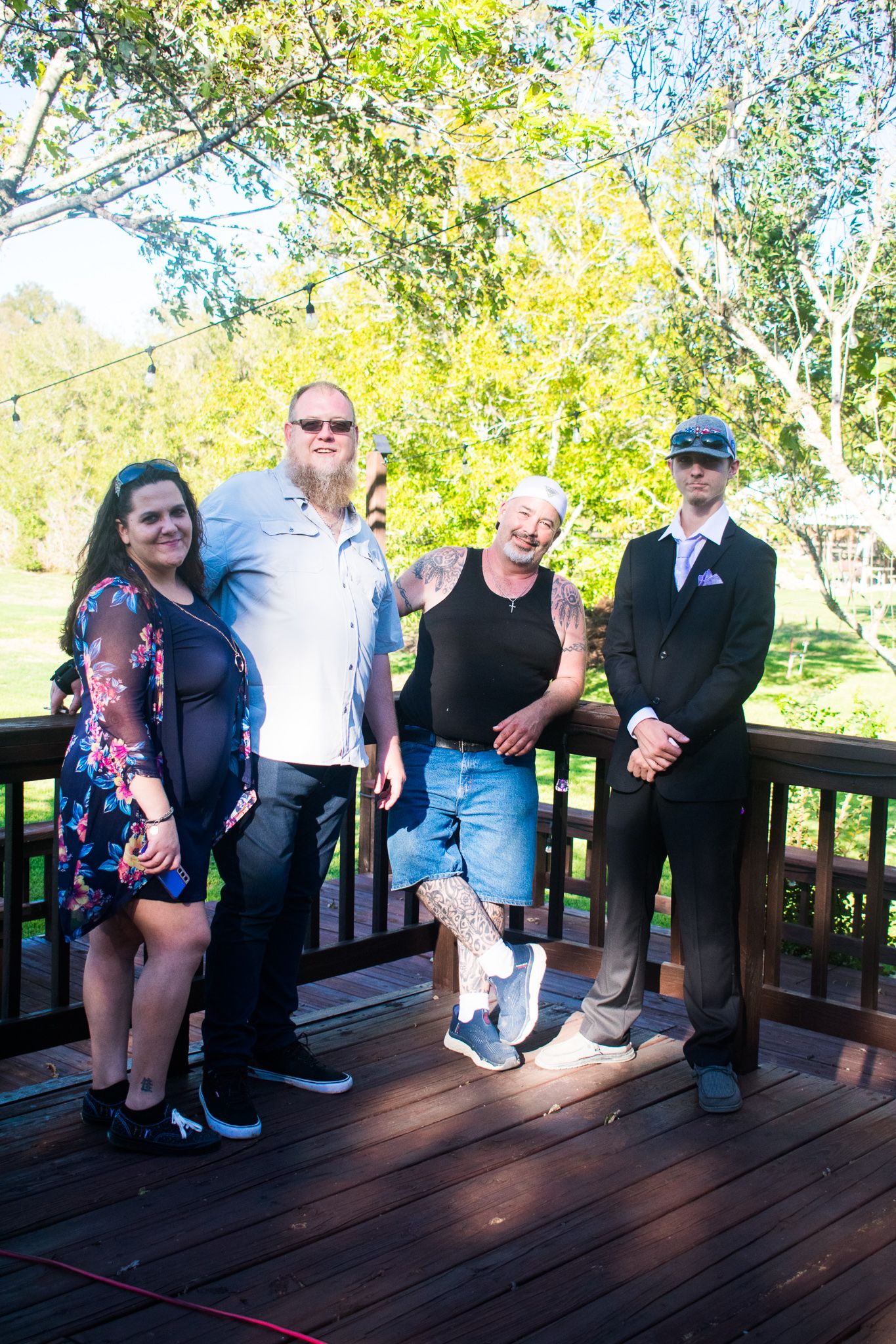 A group of people pose together on a wooden deck during a sunny afternoon.