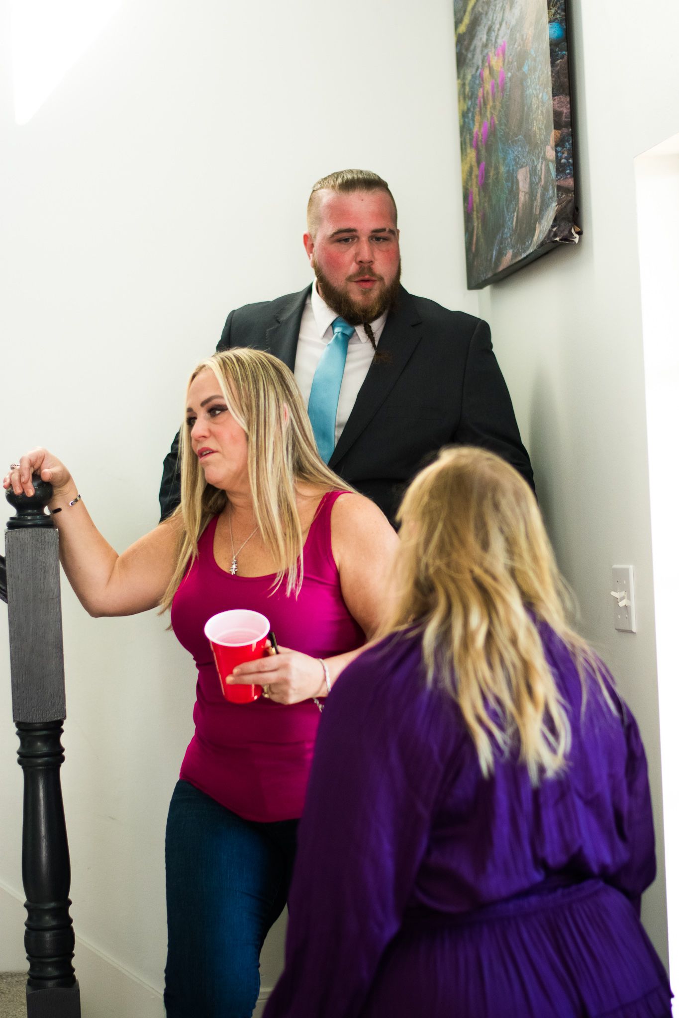 Three people having a conversation near a staircase with black bannister.