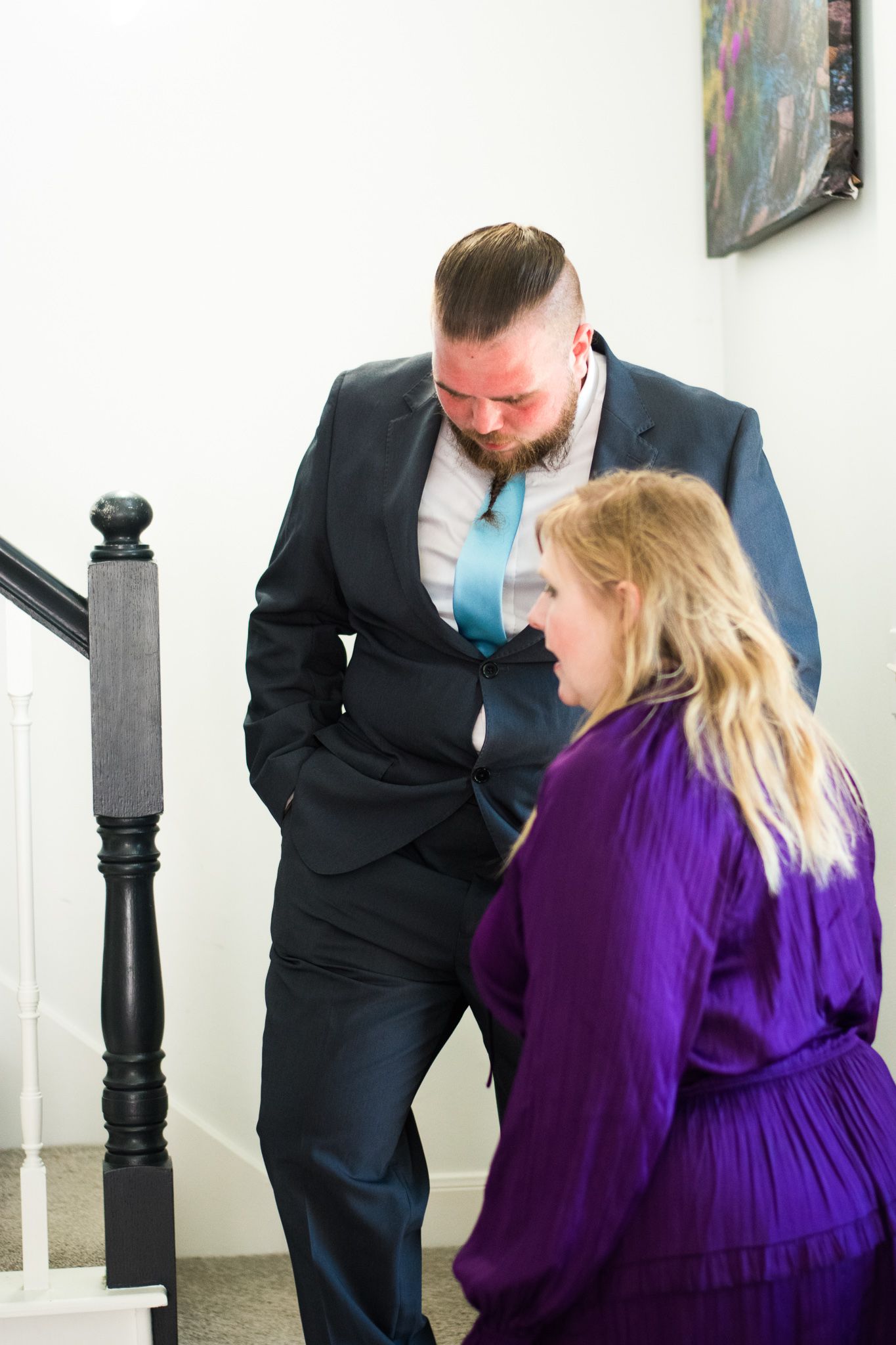 A tender moment between two people standing by a staircase bannister.