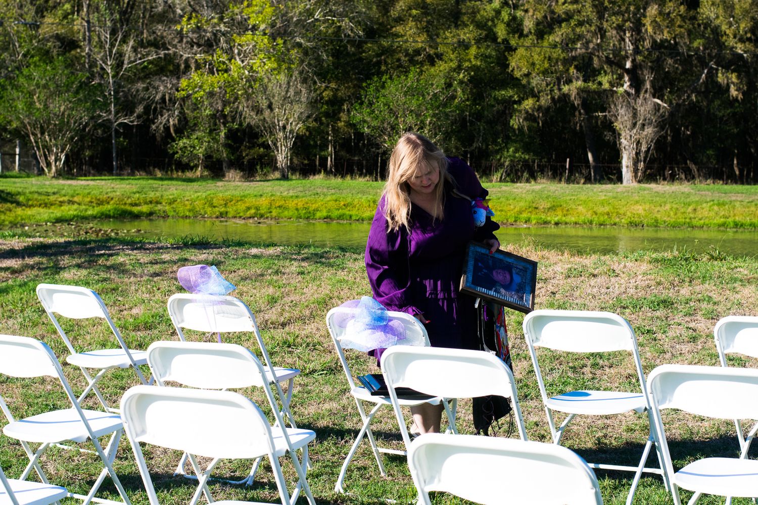 White folding chairs arranged outdoors for an event on grass.