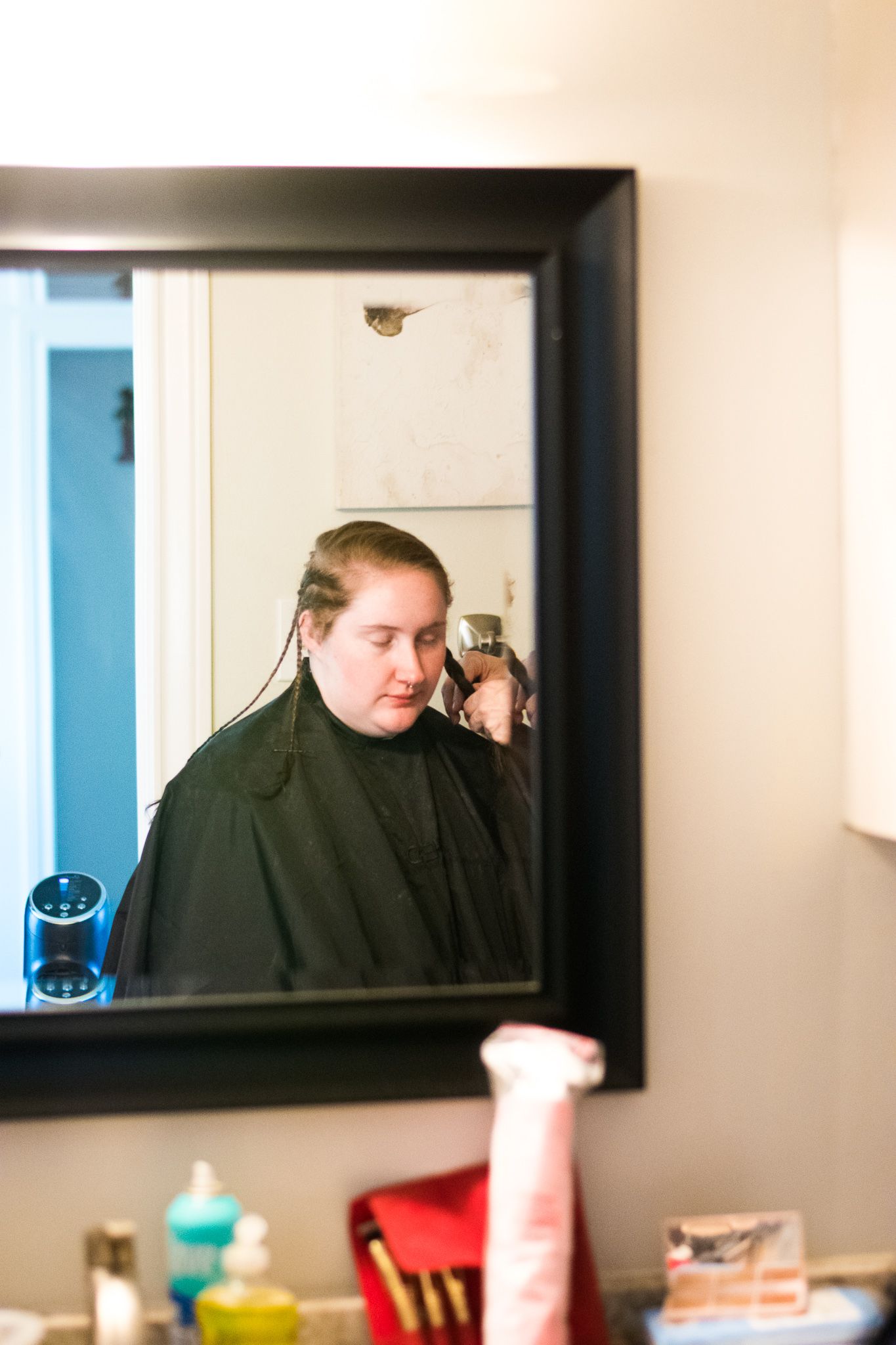 Mirror reflection of someone getting hair styled in salon.