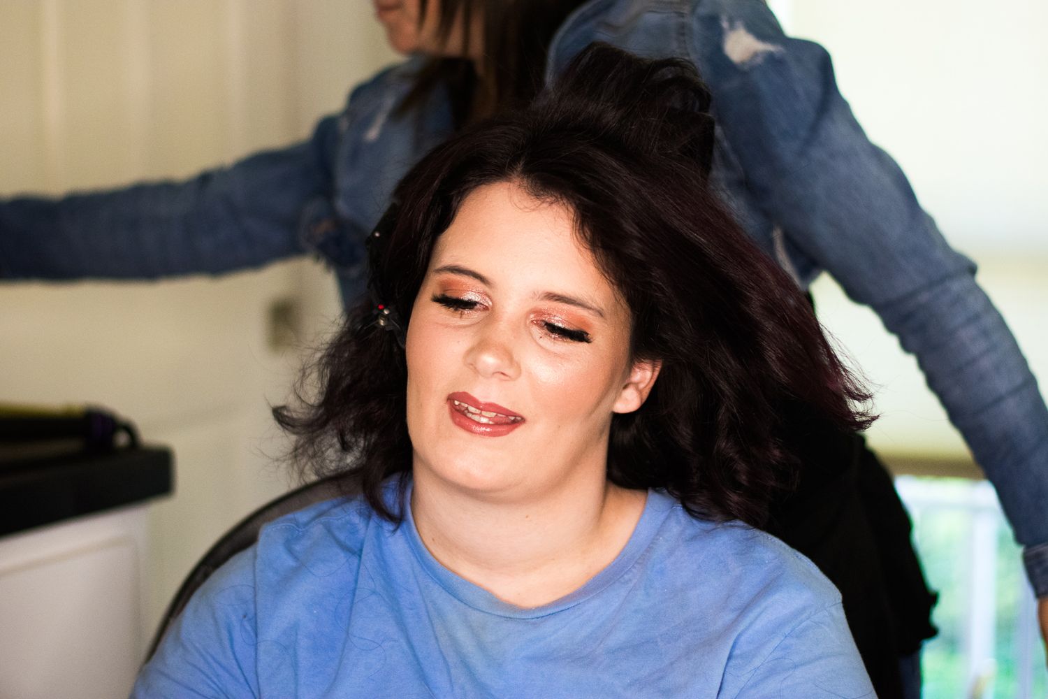 Someone getting their hair styled while smiling in a salon chair.