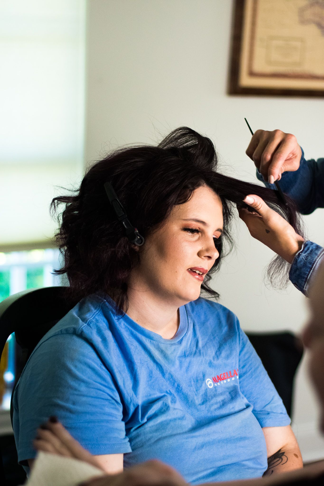 Hairstylist working on client's dark hair in salon setting.