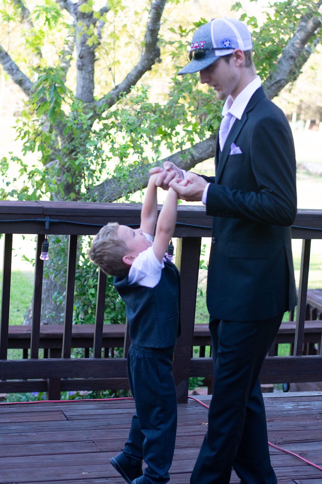 A playful moment between two people on an outdoor deck surrounded by leafy trees.