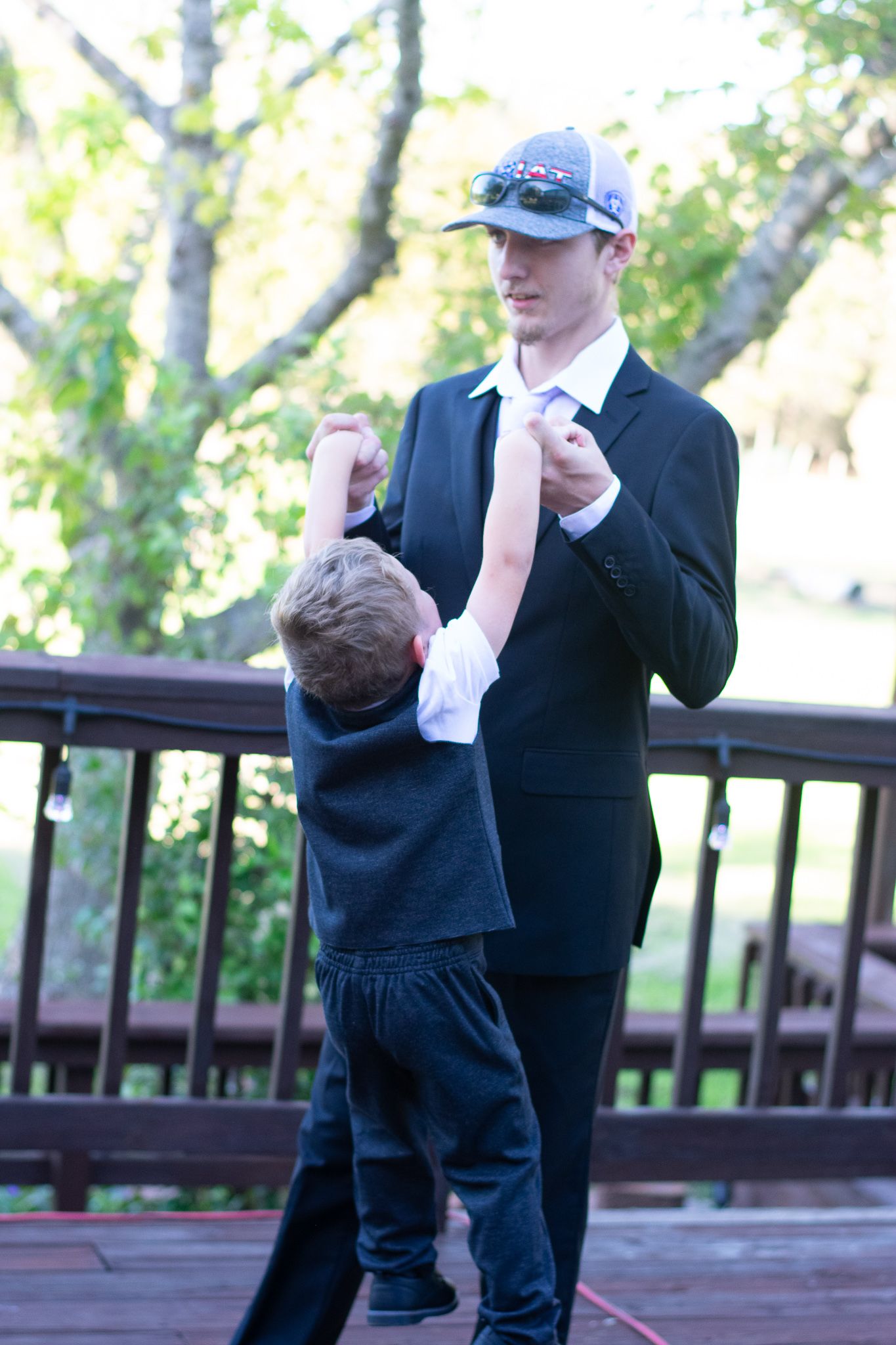 A touching interaction between two people on a wooden deck during what appears to be a formal occasion.