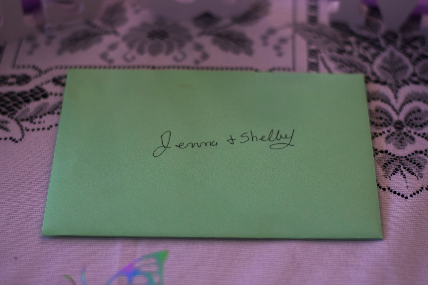 Green envelope with handwritten names on lace tablecloth.