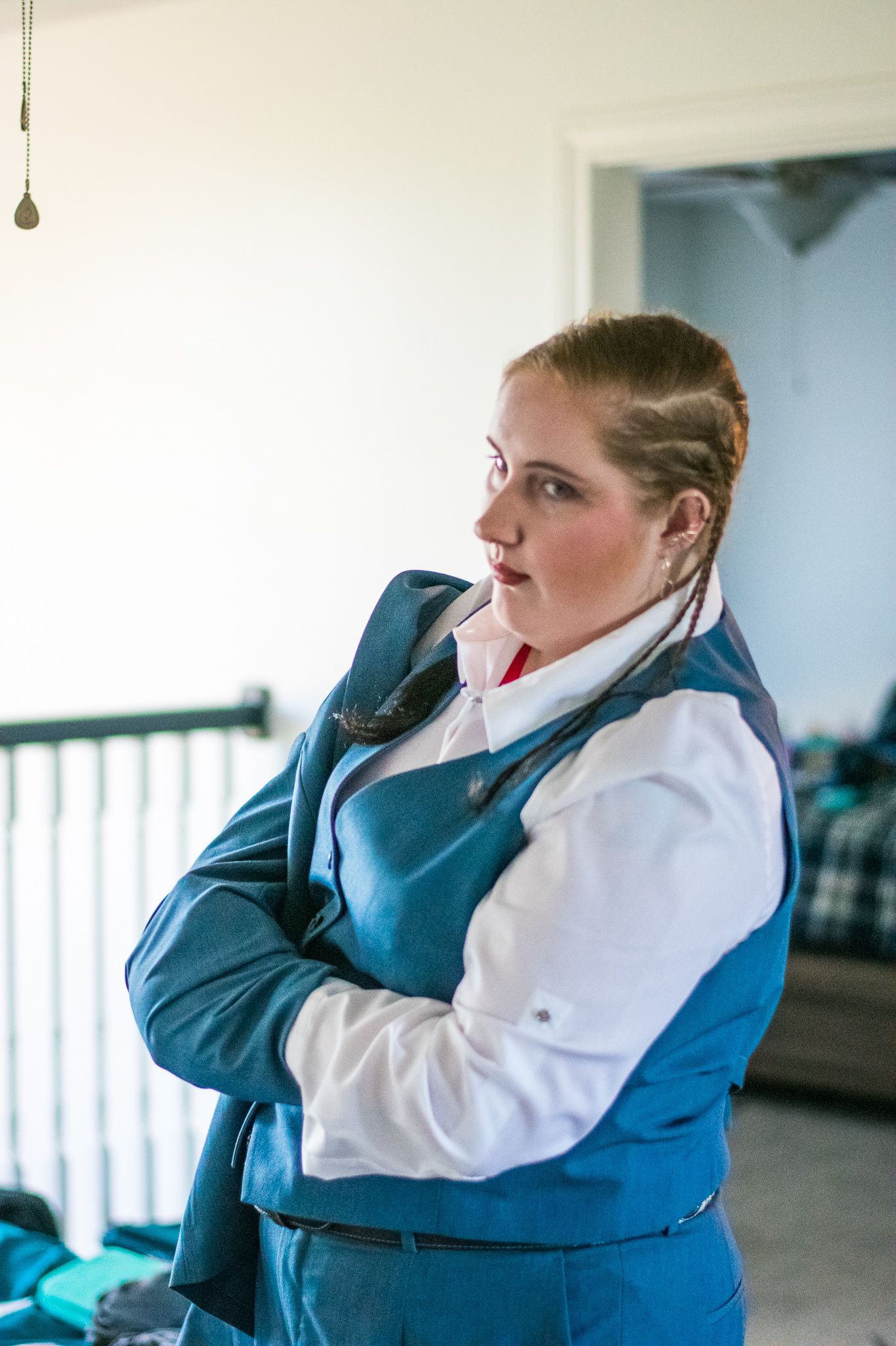 Person in formal blue suit and white shirt with braided hair styling.