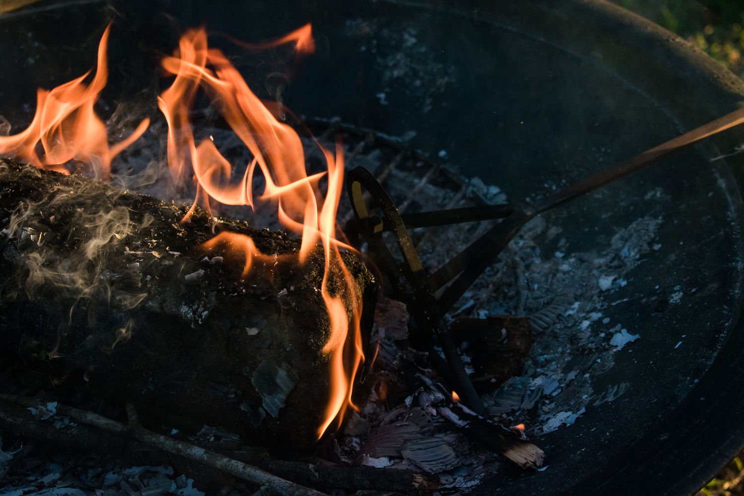 Close-up shot of flames burning in outdoor fire pit at dusk.