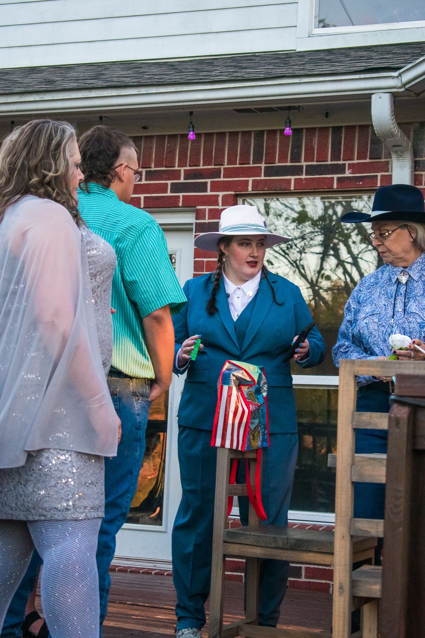 Group gathered on a deck with one wearing a blue suit and patriotic decorations.