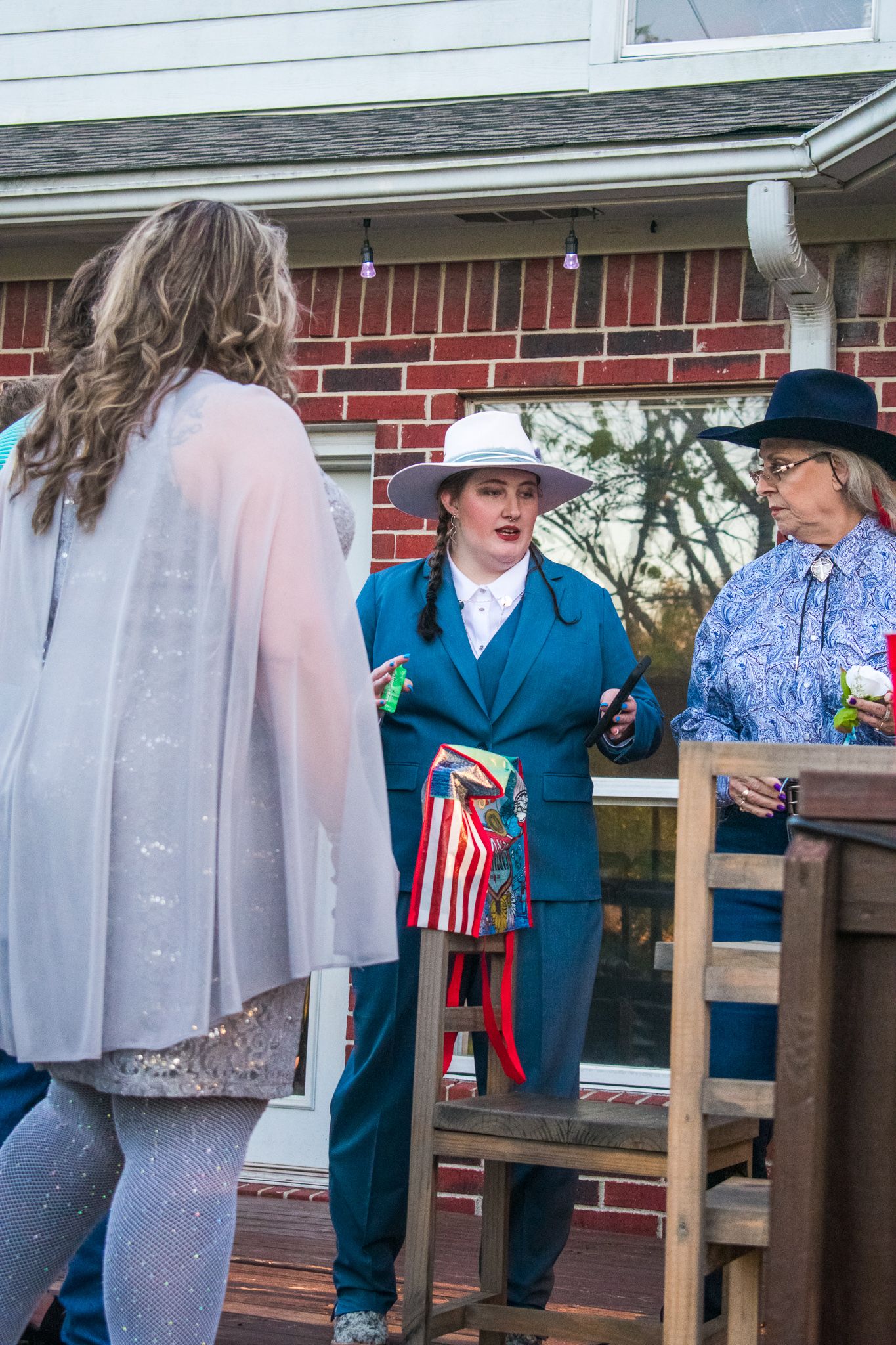 People conversing on a wooden deck with patriotic decorations and casual attire.